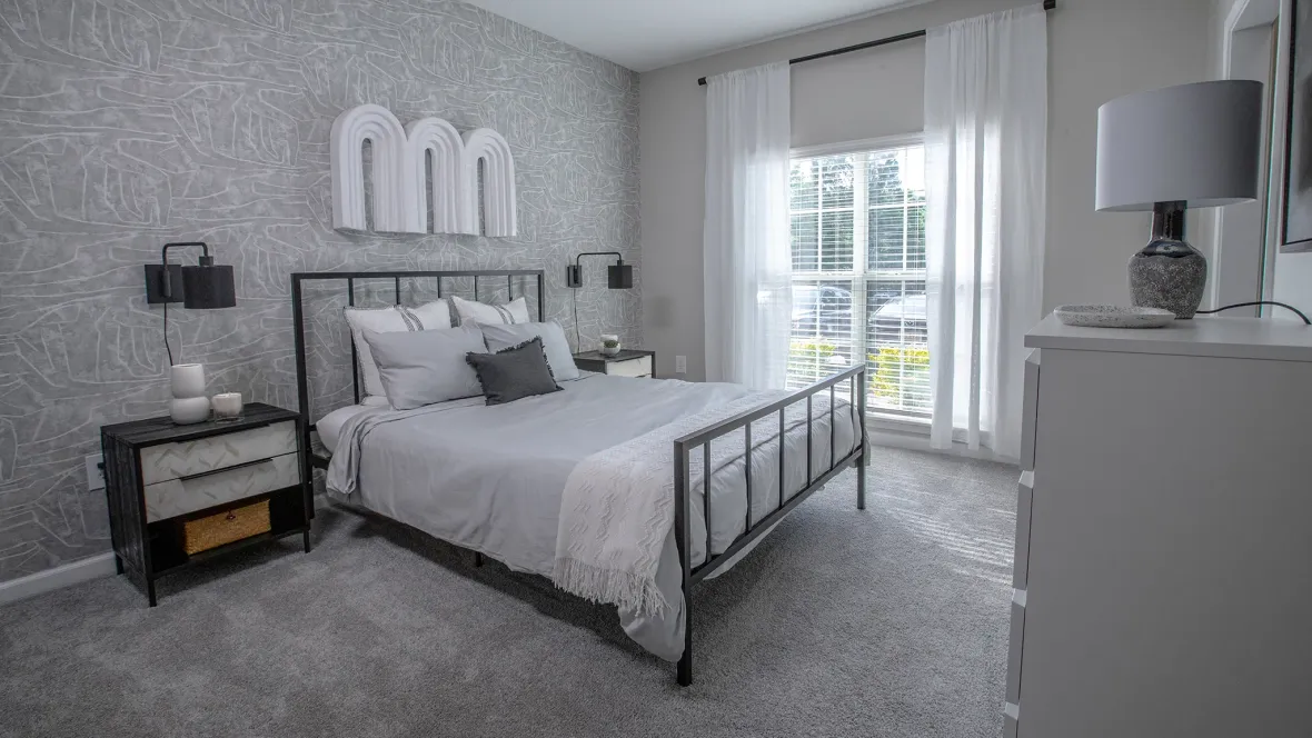 A large, spacious bedroom with tan carpet and a large window