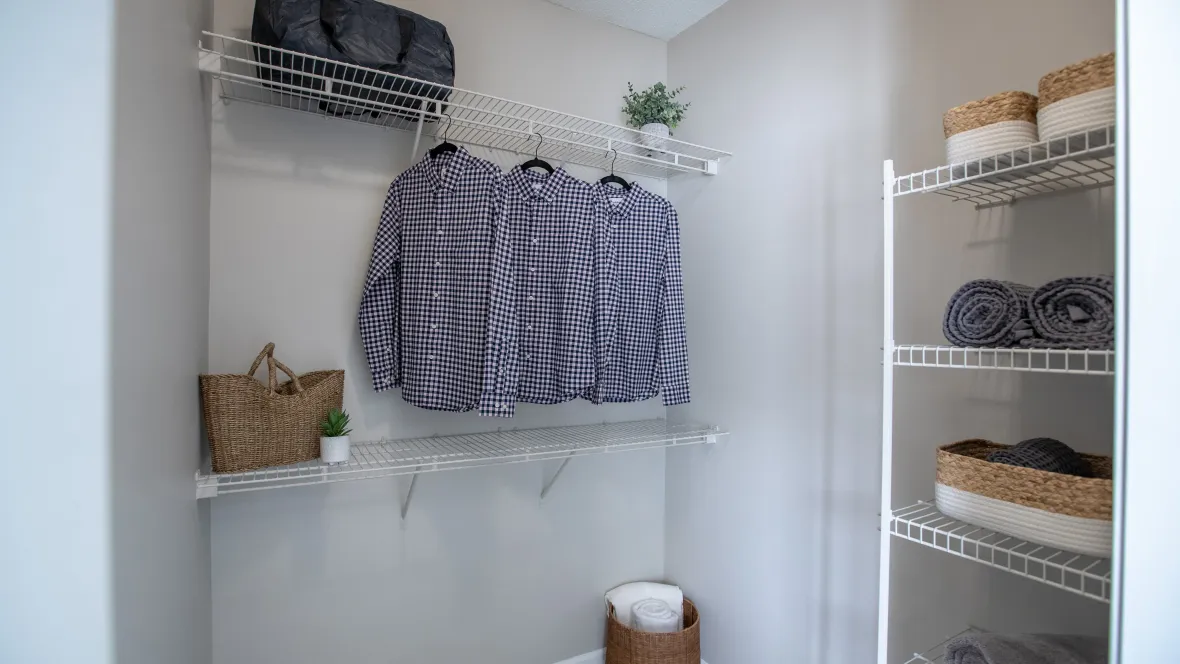 Large closet with built-in staggered shelving for multiple levels of hanging and storage.