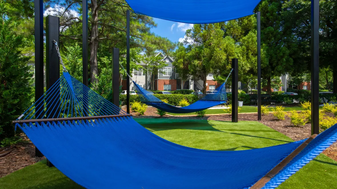 Two bright blue hammocks with shades suspended over them.