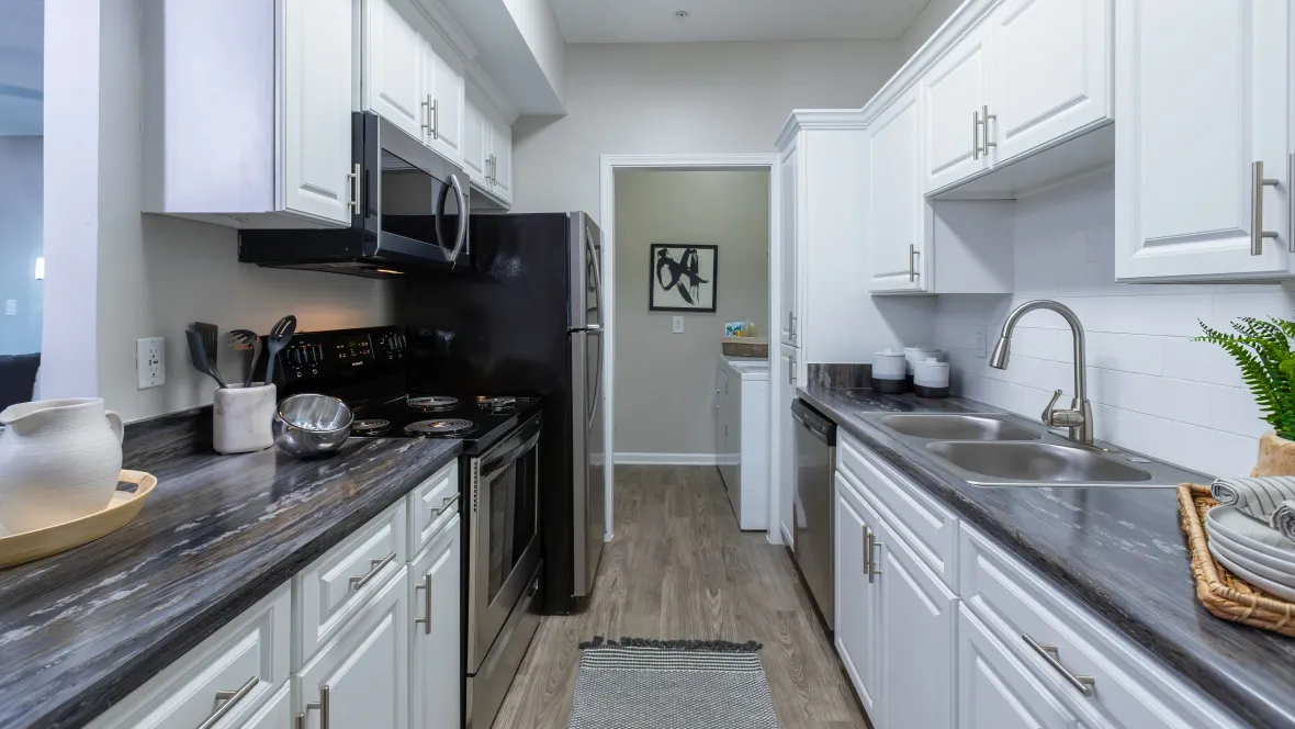 A view into the kitchen with black fusion countertops and stainless steel appliances from the breakfast bar.