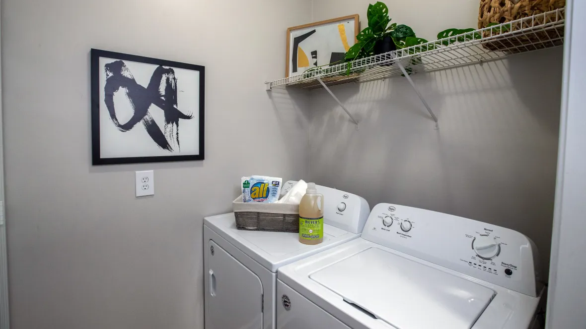 Laundry room with full size washer and dryer appliances and built-in storage shelving.