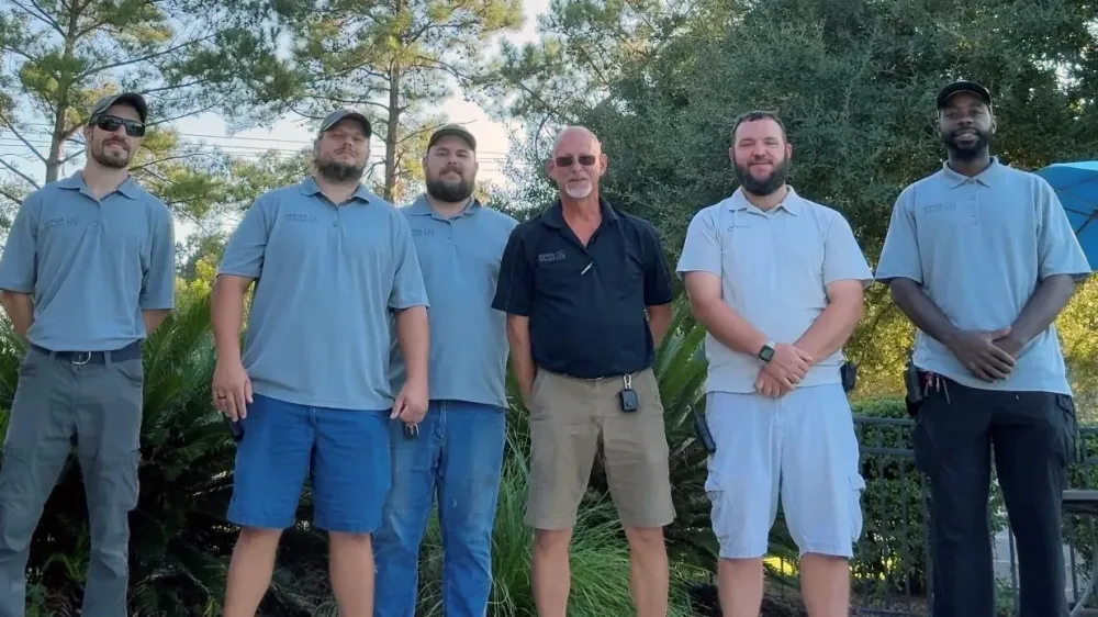 Eagle’s Pointe apartment maintenance team posing outdoors in work uniforms.