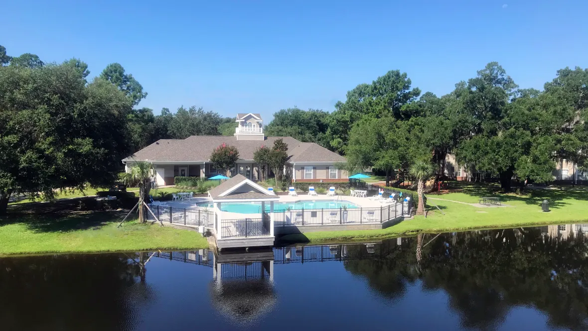 A mesmerizing aerial view of Eagle's Pointe, featuring a resort-style pool and clubhouse by the serene lake, nestled among lush green trees that frames this idyllic community.