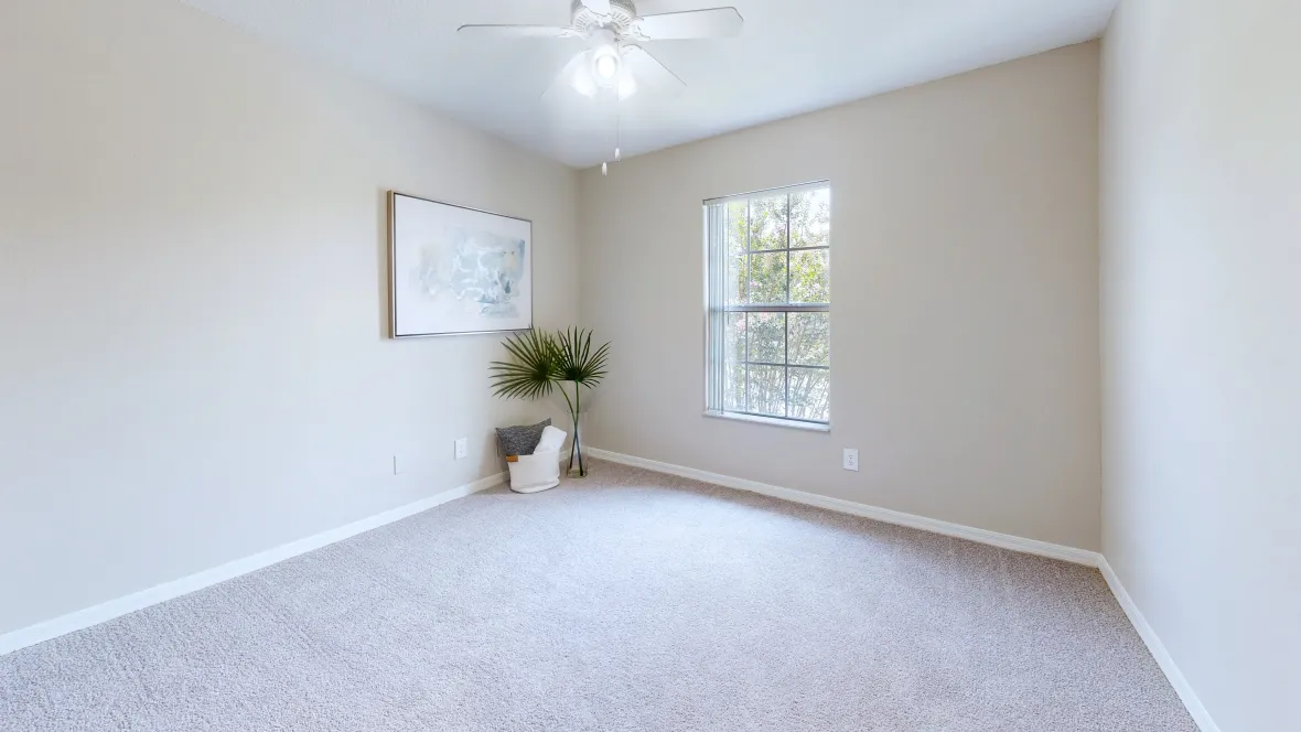 A peaceful carpeted guest room featuring a bright window that infuses the space with natural light, fostering a cozy atmosphere.