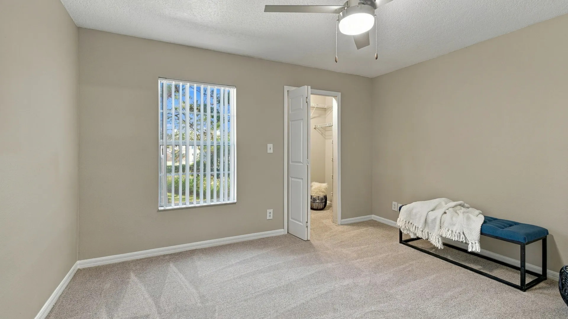 Bedroom at Eagle's Pointe featuring plush carpeting, a ceiling fan, a large window with natural light, and a walk-in closet with built-in shelving.