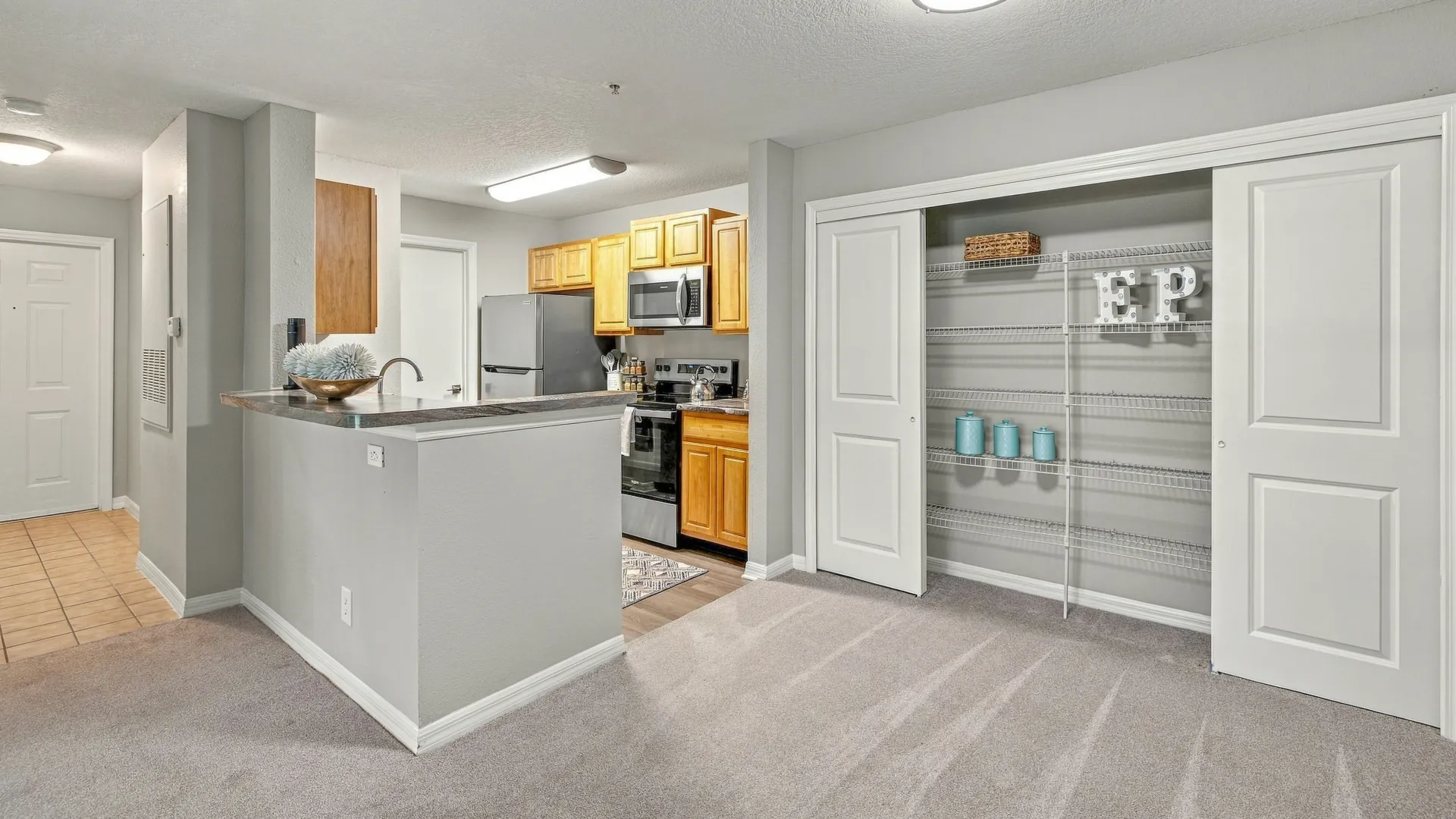 Dining area at Eagle's Pointe featuring plush carpeting, a breakfast bar, open access to the kitchen, and a large pantry closet with built-in shelving.