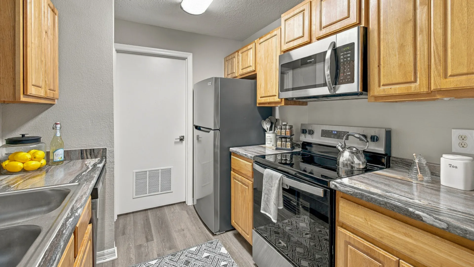 Modern kitchen at Eagle's Pointe with stainless steel refrigerator, microwave, and range, complemented by wood cabinetry and ample countertop space.