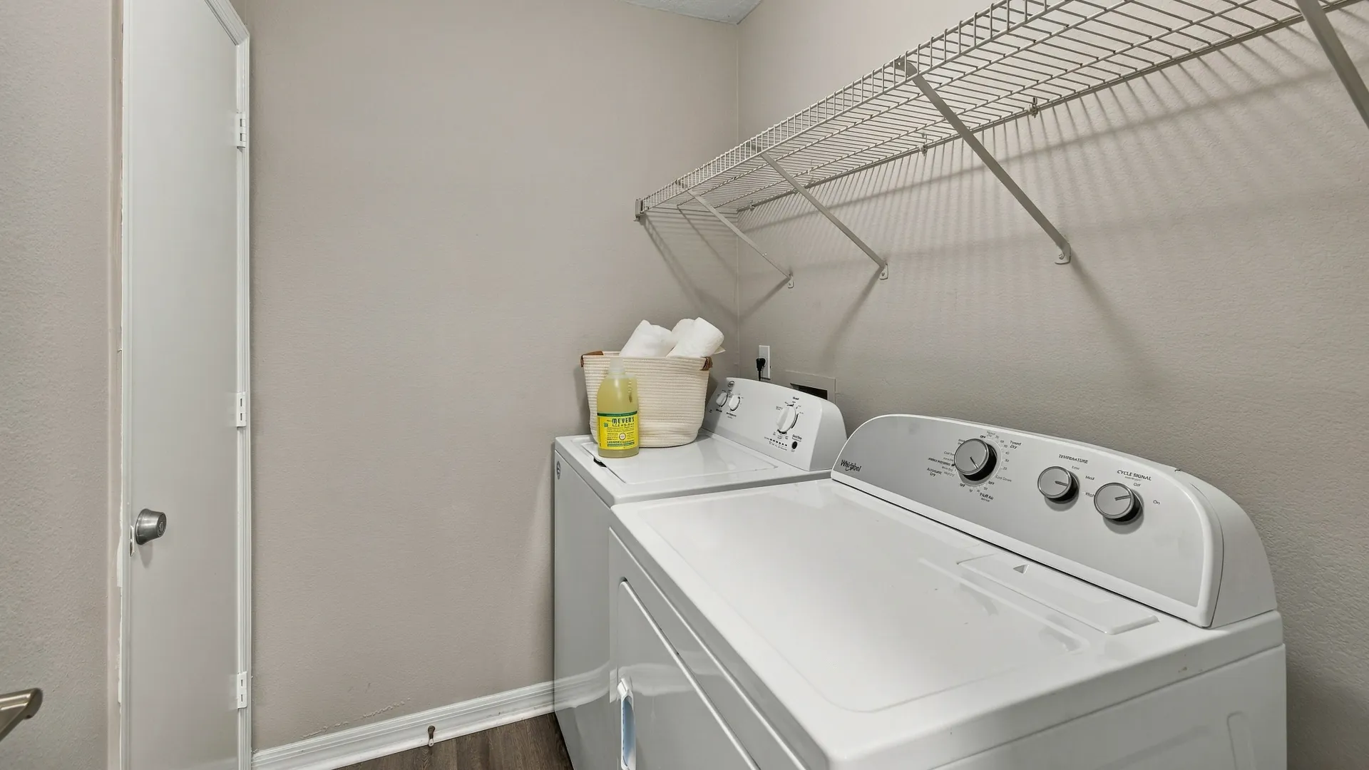 Laundry room at Eagle's Pointe featuring a full-size washer and dryer, overhead wire shelving, and wood-style flooring.