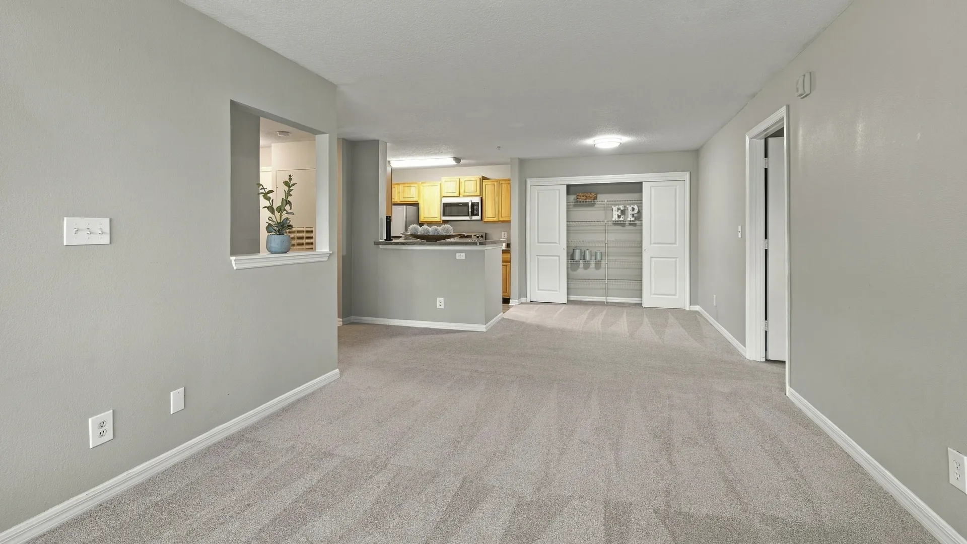 Open-concept floor plan at Eagle's Pointe featuring a spacious living area, dining space, breakfast bar, kitchen, and pantry storage in one connected layout.