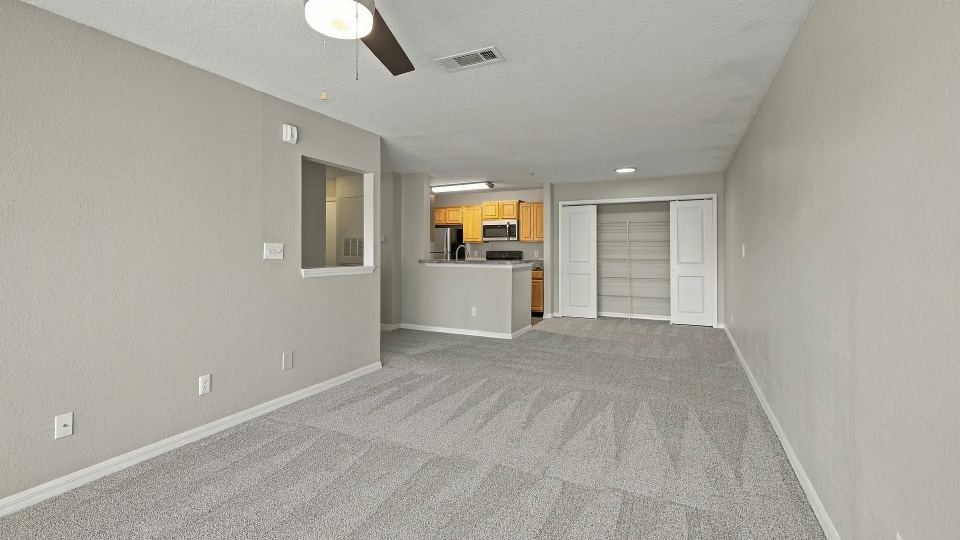 Open-concept layout in The Port floor plan featuring connected living, dining, and kitchen spaces, a breakfast bar, pantry storage, and plush carpeting.