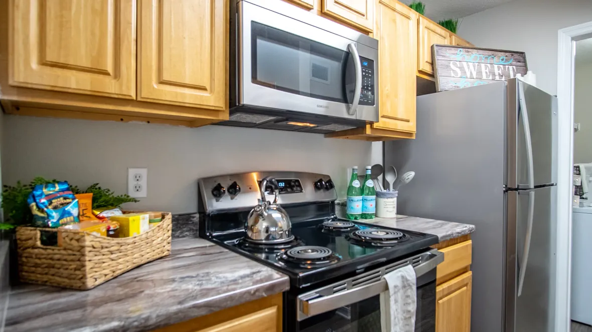 Eagle's Pointe's signature kitchen, featuring stainless steel stove, microwave, and refrigerator as well as a beautiful black fusion countertop for culinary masterpieces.