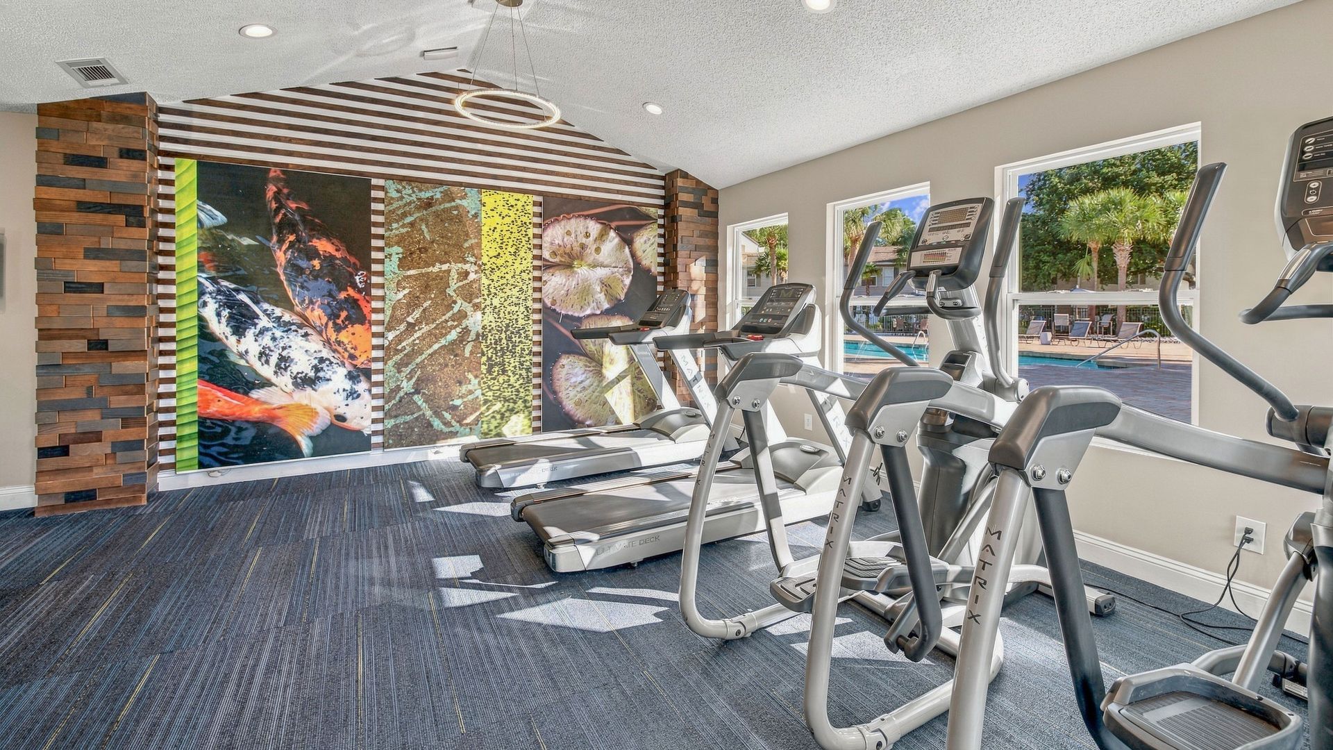 Fitness center at Lanier Landing featuring treadmills, elliptical machines, large windows, modern lighting, and views of the resort-style swimming pool.