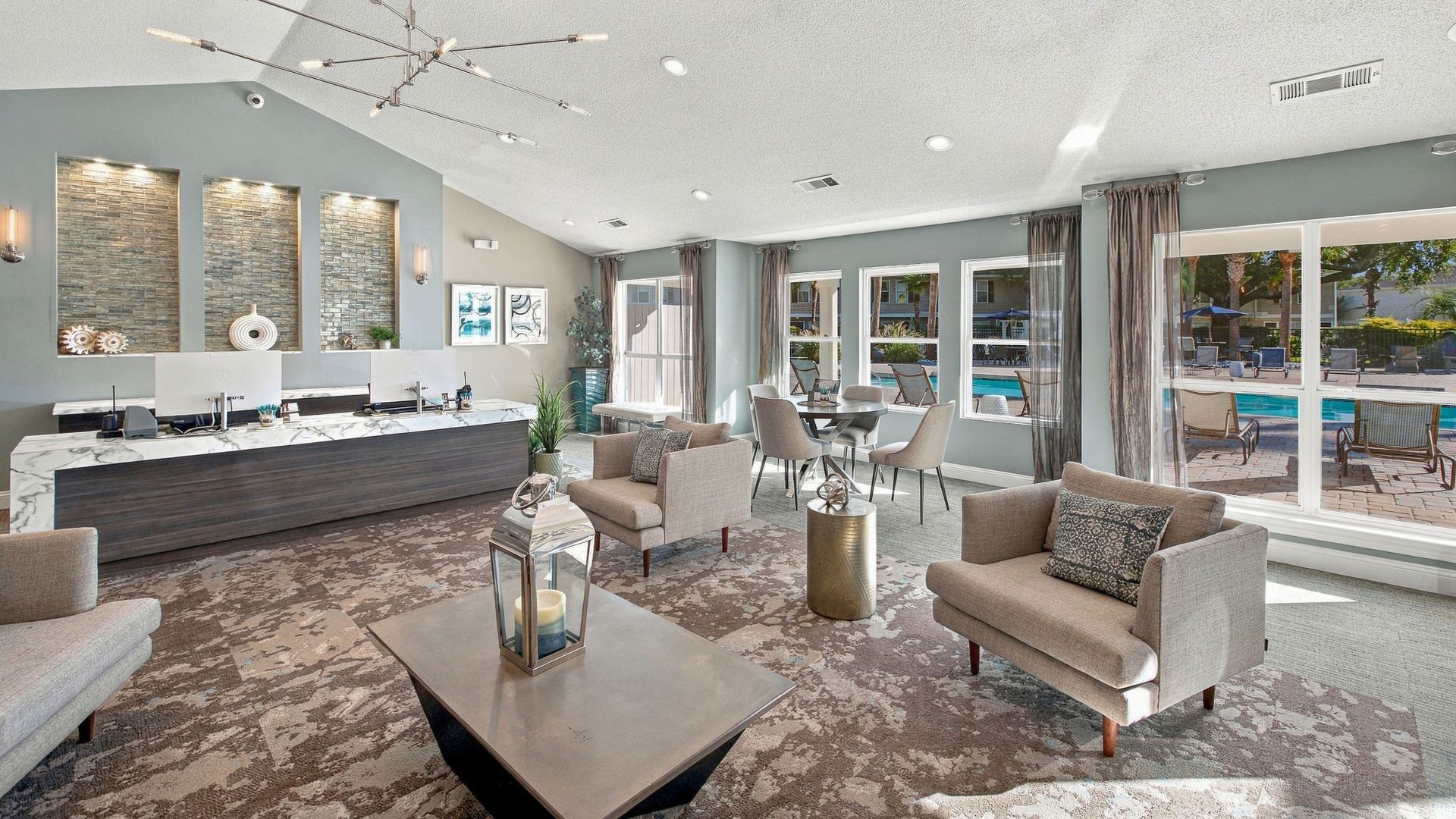 Leasing office at Lanier Landing featuring a modern reception desk, comfortable lounge seating, large windows, upscale finishes, and views of the community pool.