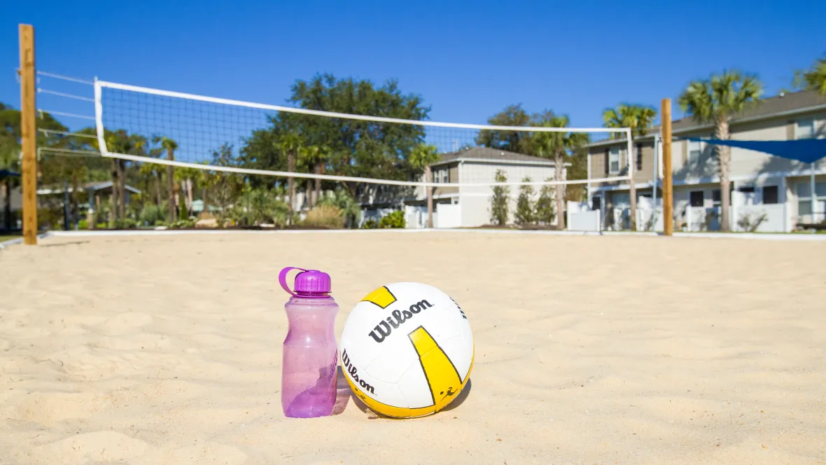 A sandy outdoor court with a perfectly stretched net and volleyball ready for play.