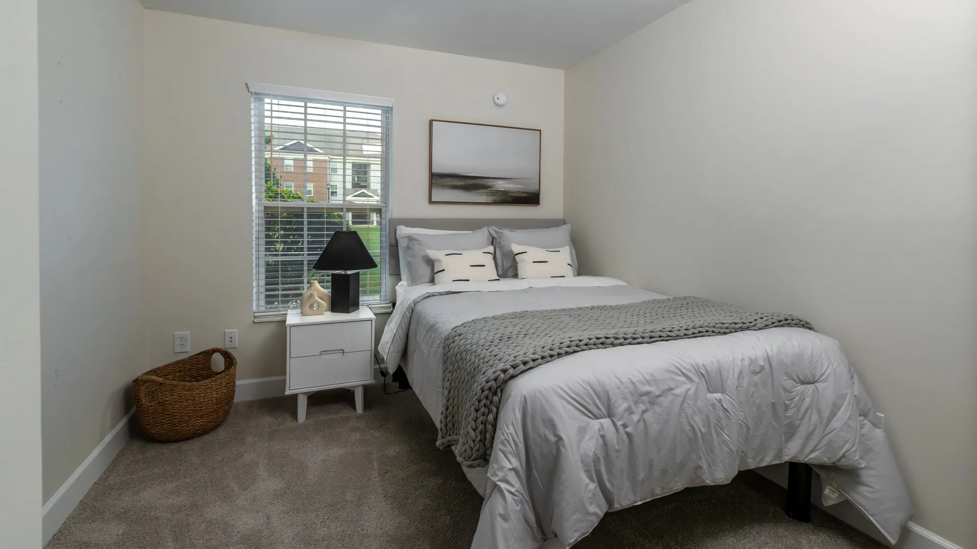 Modern bedroom at The Foundry Apartments with a stylish bed, nightstand, and window view.