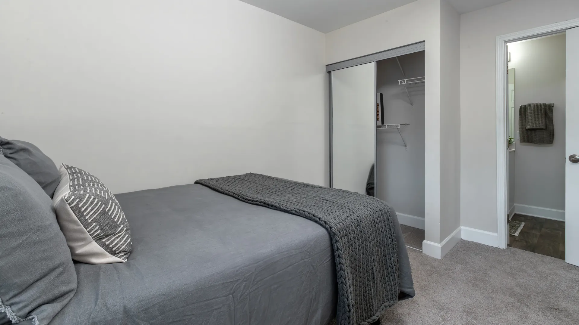 A bedroom with a mirrored closed door looking into a large spacious closet 