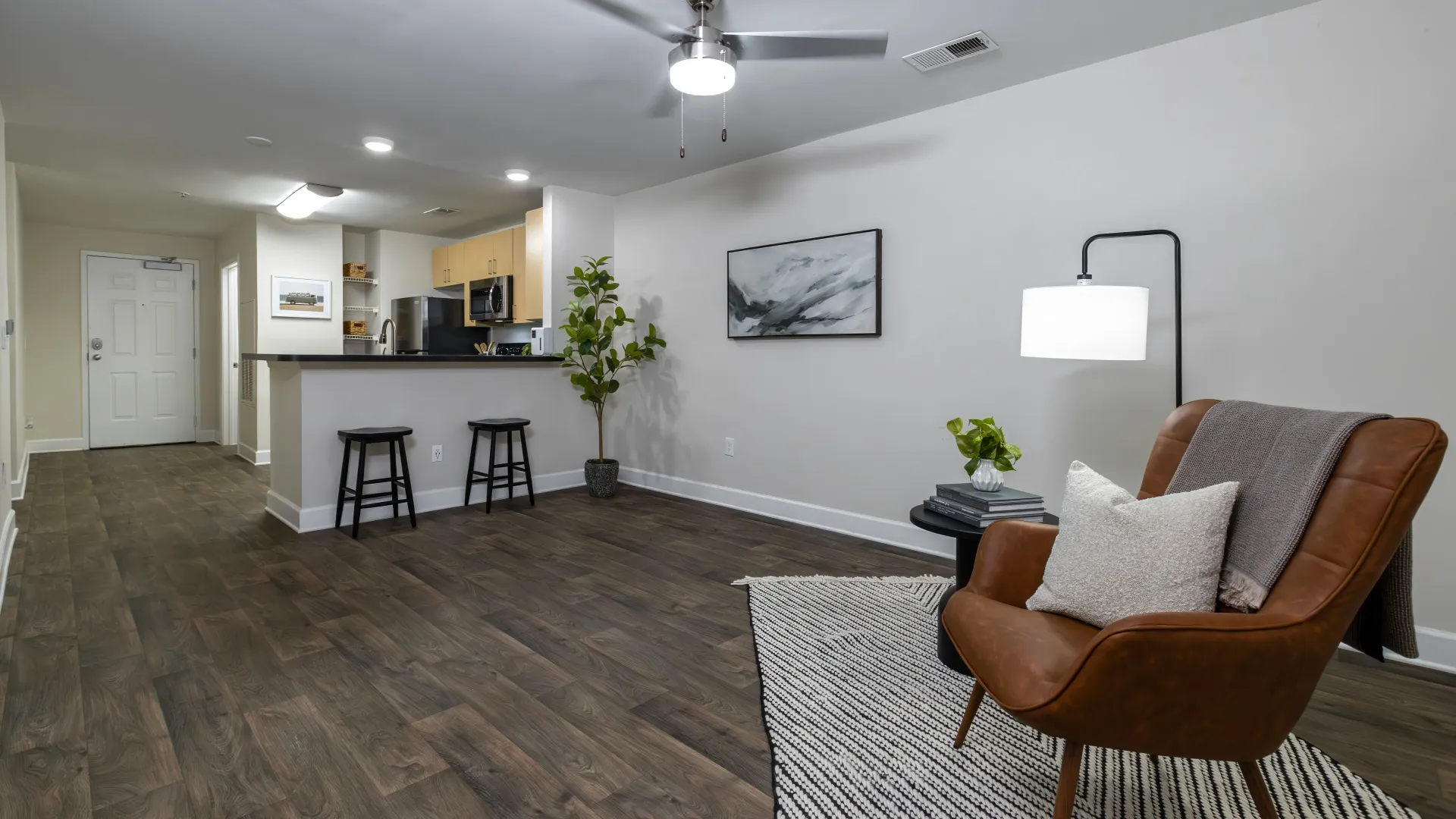 Modern living room at The Foundry Apartments featuring wood-style flooring, open kitchen, and cozy seating area.