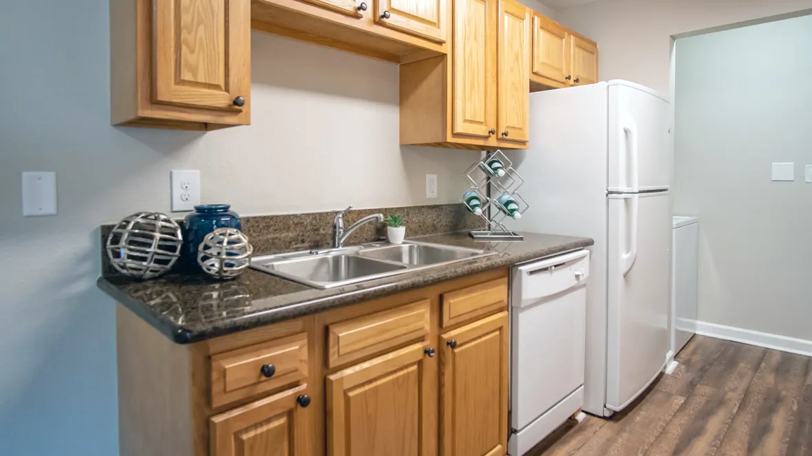 A traditional kitchen space featuring shiny countertops, solid oak cabinetry, and a full range of classic white appliances, including a coveted dishwasher, offering a timeless ambiance.