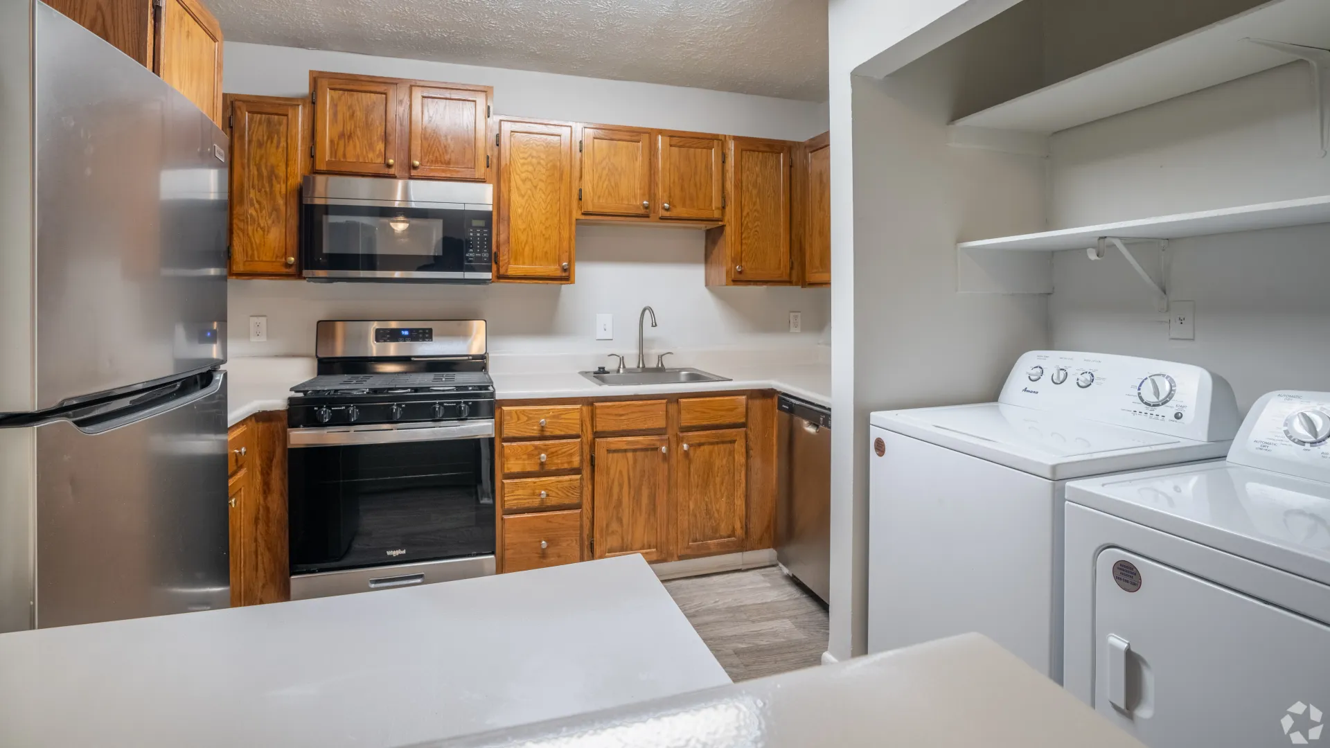 Kitchen with stainless steel appliances, wooden cabinets, and an in-unit washer and dryer in The Whitlock floor plan.