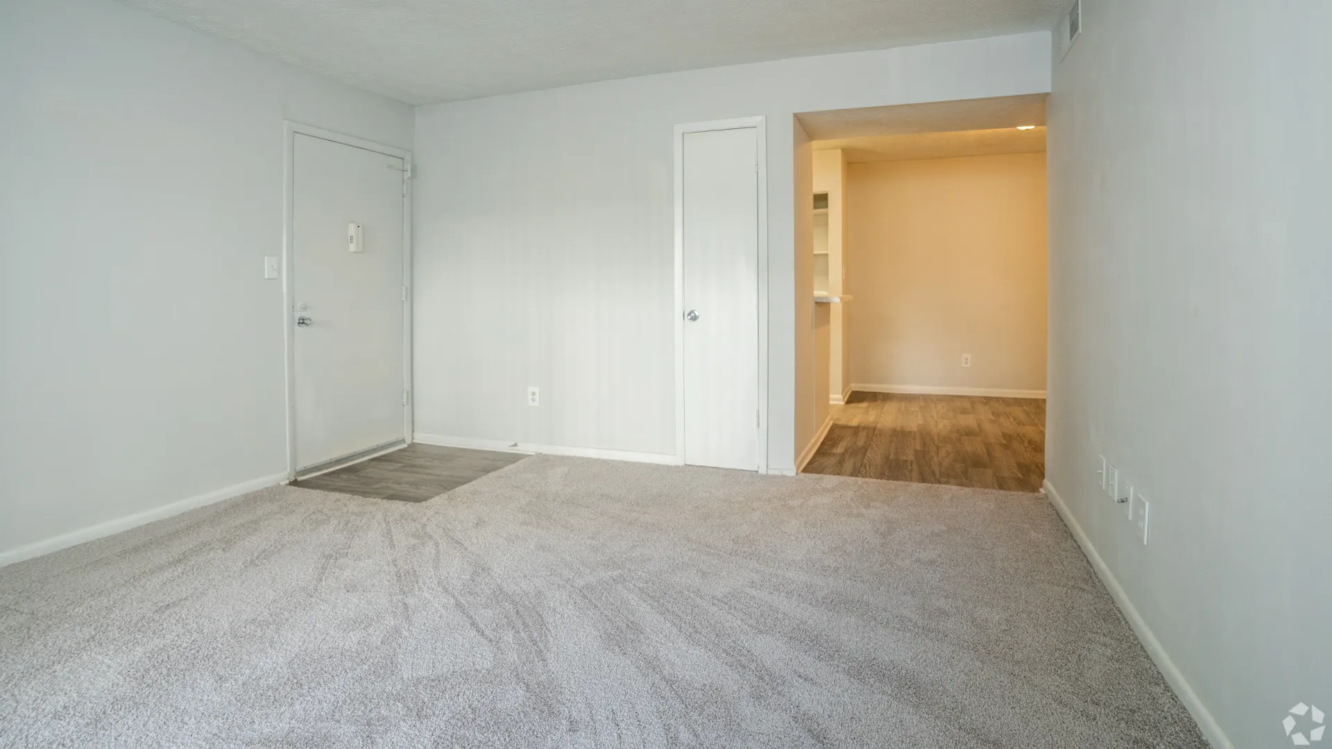 Open living room area in The Whitlock floor plan with plush carpeting and neutral walls.