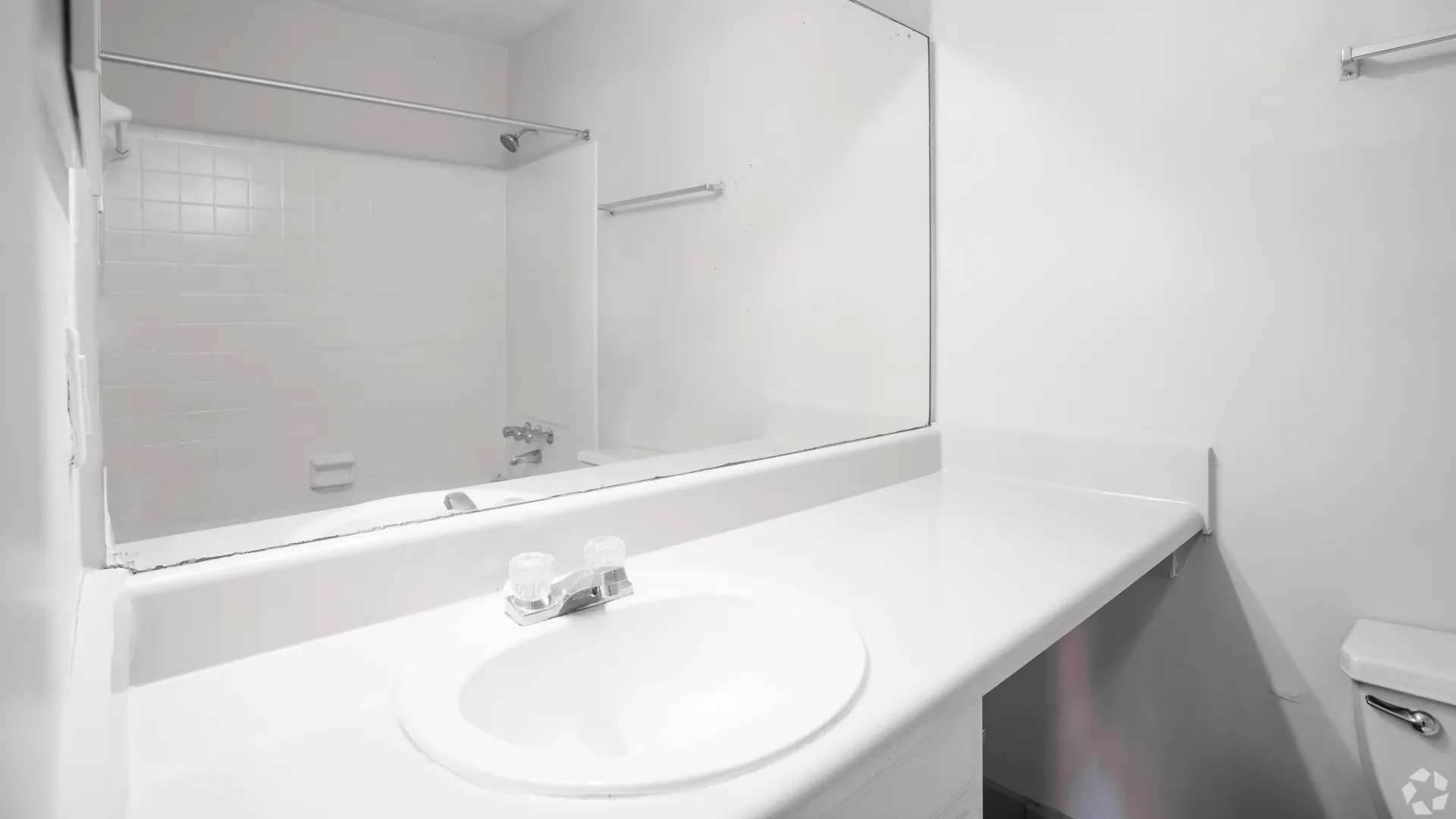 Master bathroom in The Whitlock floor plan featuring a large vanity, mirror, and bathtub in a clean, white finish.