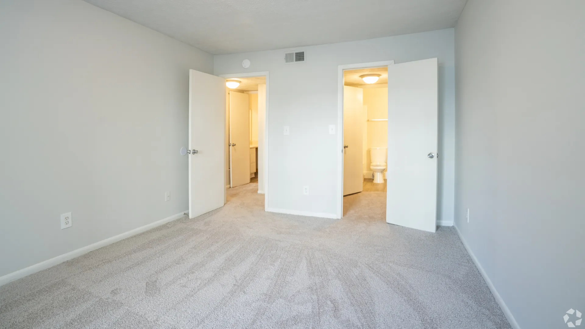 Master bedroom in The Whitlock floor plan featuring plus carpeting, two doorways, and access to the master bathroom.