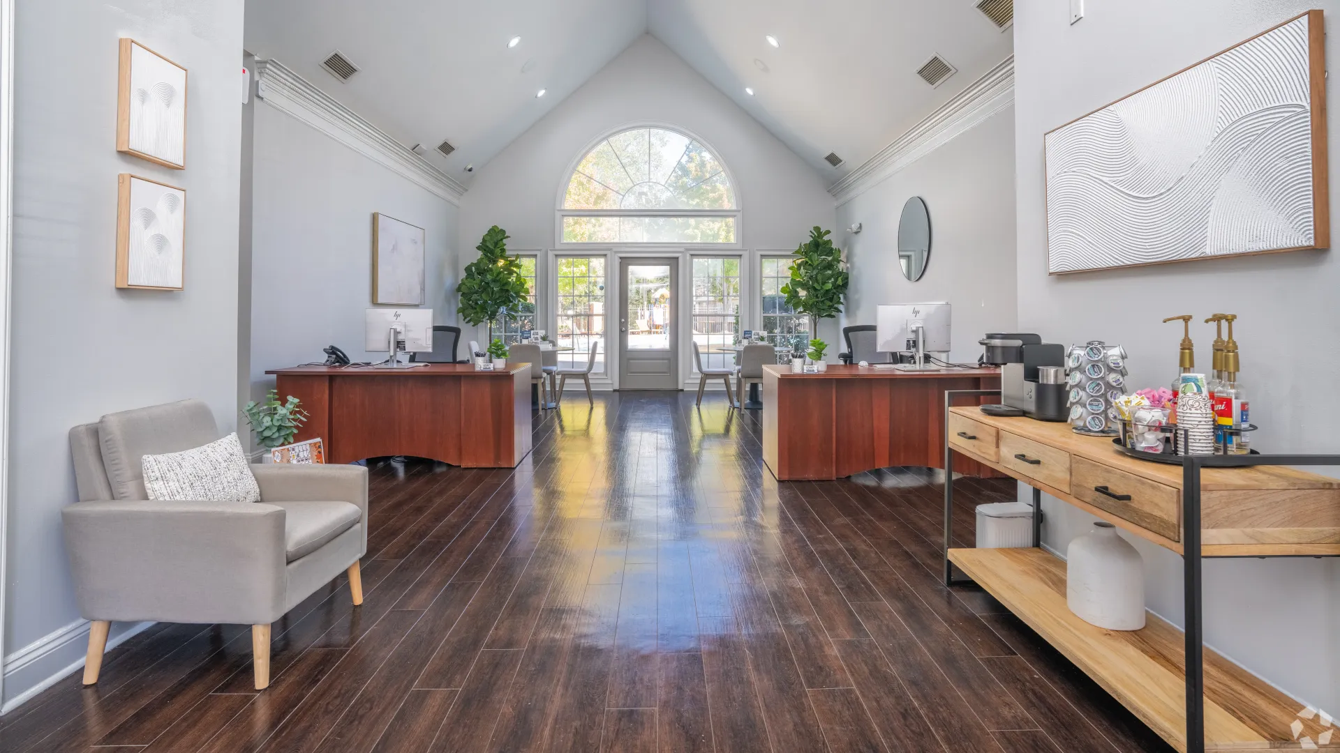 Leasing office at Legacy at West Cobb Apartments featuring a modern design with wood floors, desk seating areas, plants, and a complimentary coffee station.