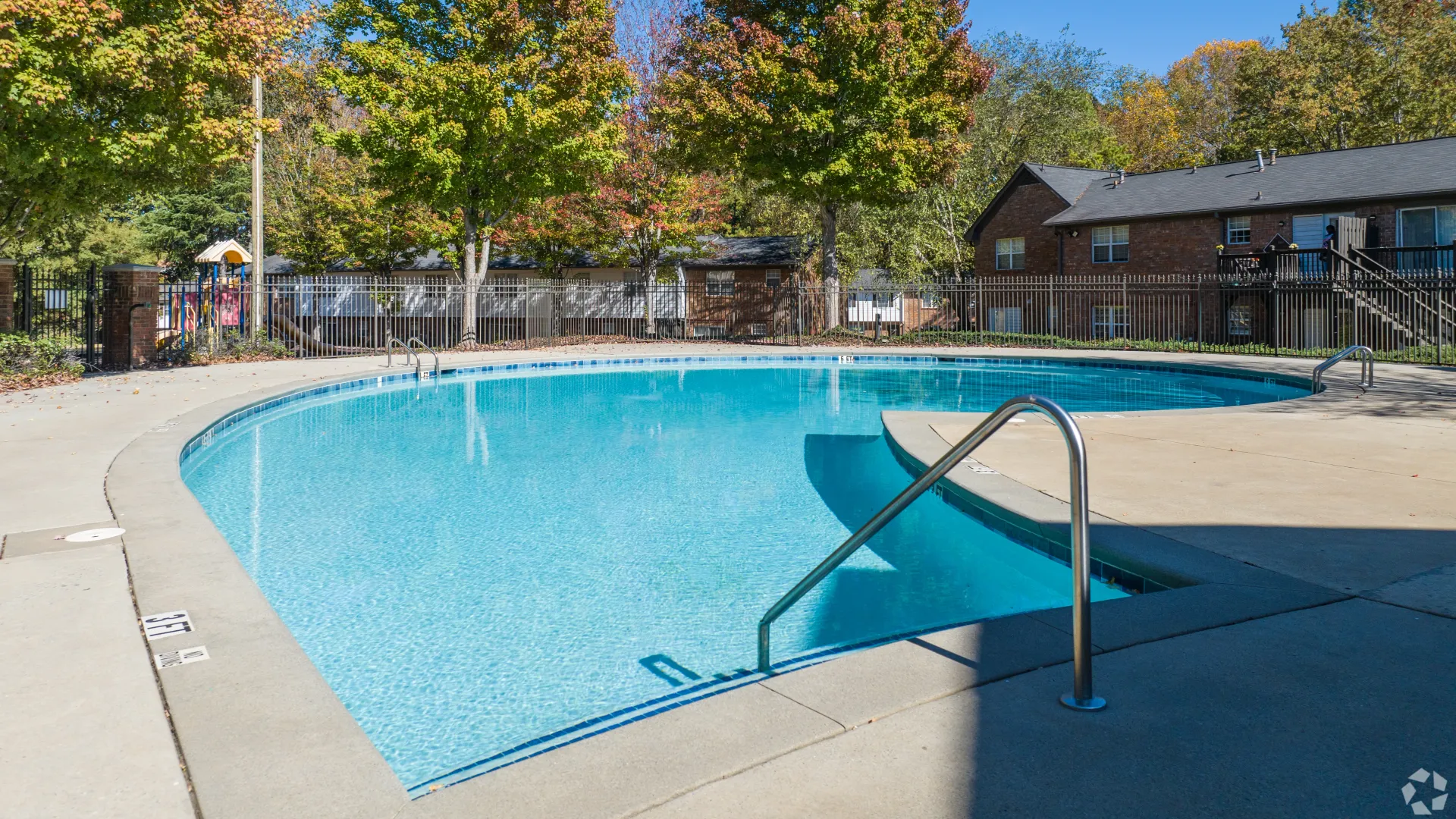 Outdoor pool at Legacy at West Cobb Apartments with clear water, surrounded by a fence and shaded trees in the background.