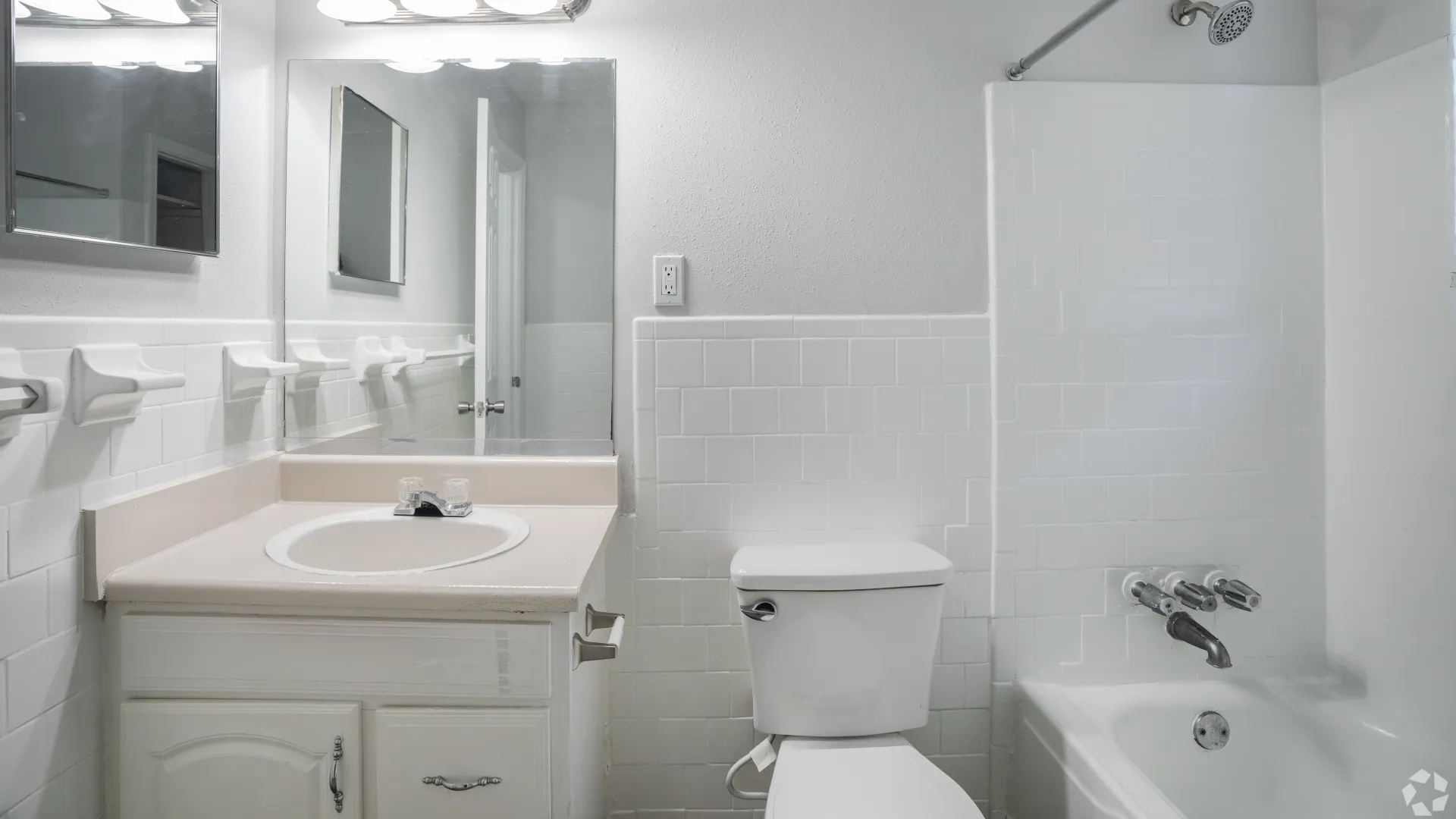 The bathroom in The Roswell floor plan featuring a large vanity, mirror, toilet, and bathtub with tiled walls.