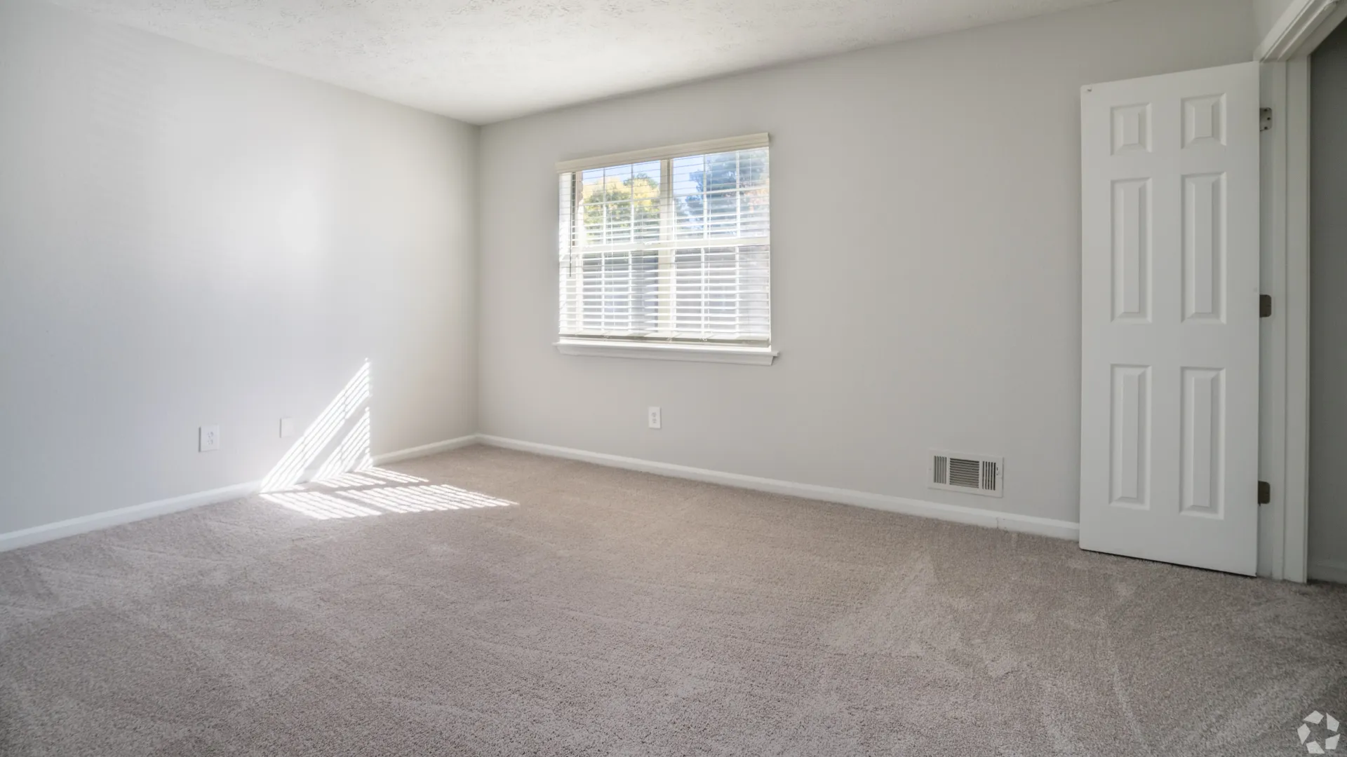 Bright bedroom with carpet flooring and a large window in The Roswell floor plan at Legacy at West Cobb.