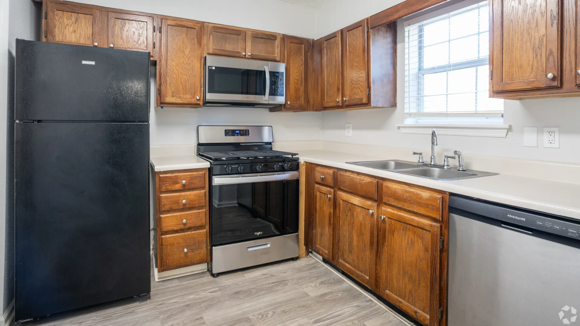 Kitchen in The Roswell floor plan featuring dark appliances, wooden cabinets, and a double sink.