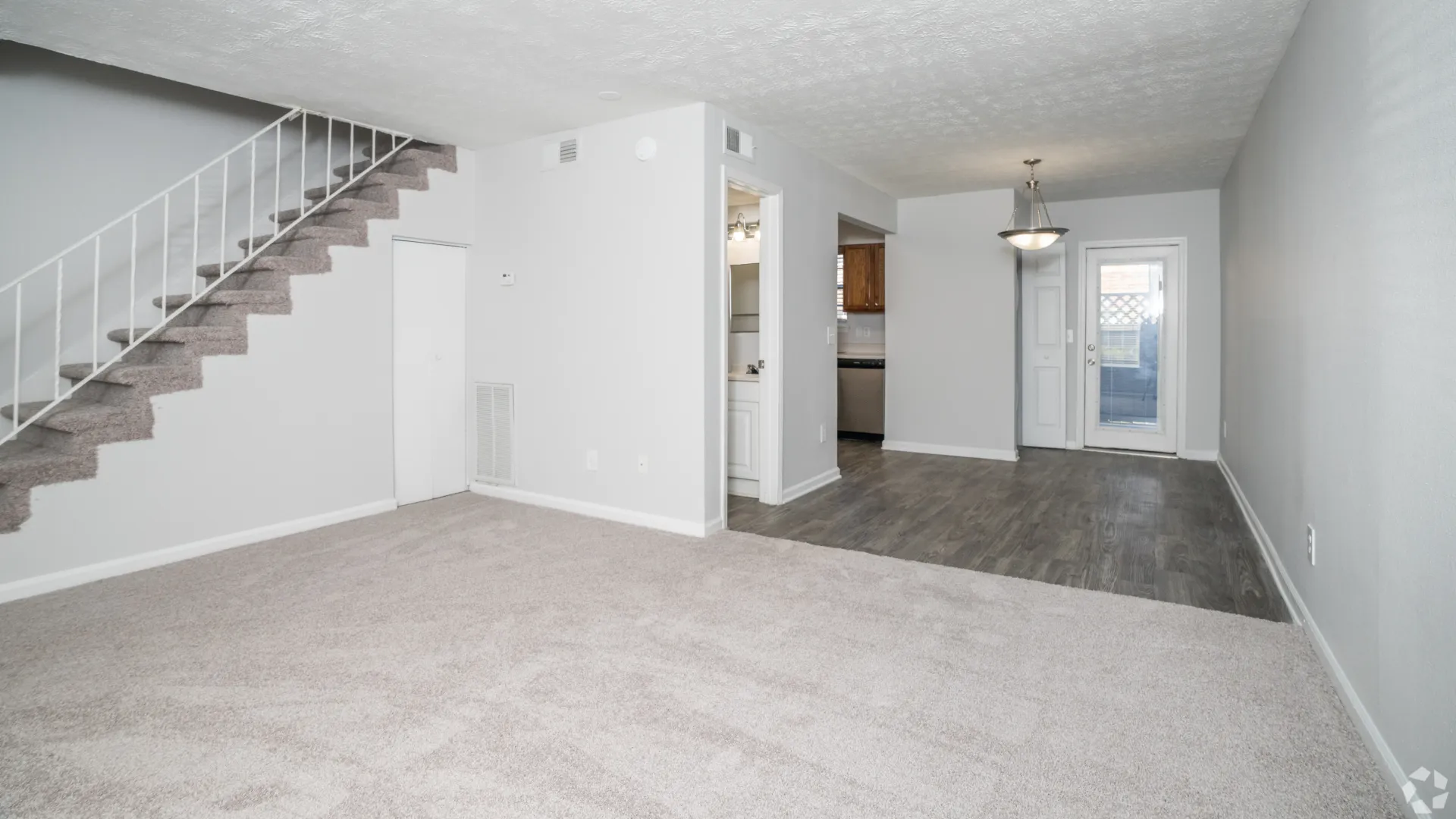 Living room in The Roswell floor plan featuring carpeted flooring, staircase, and access to the dining area.