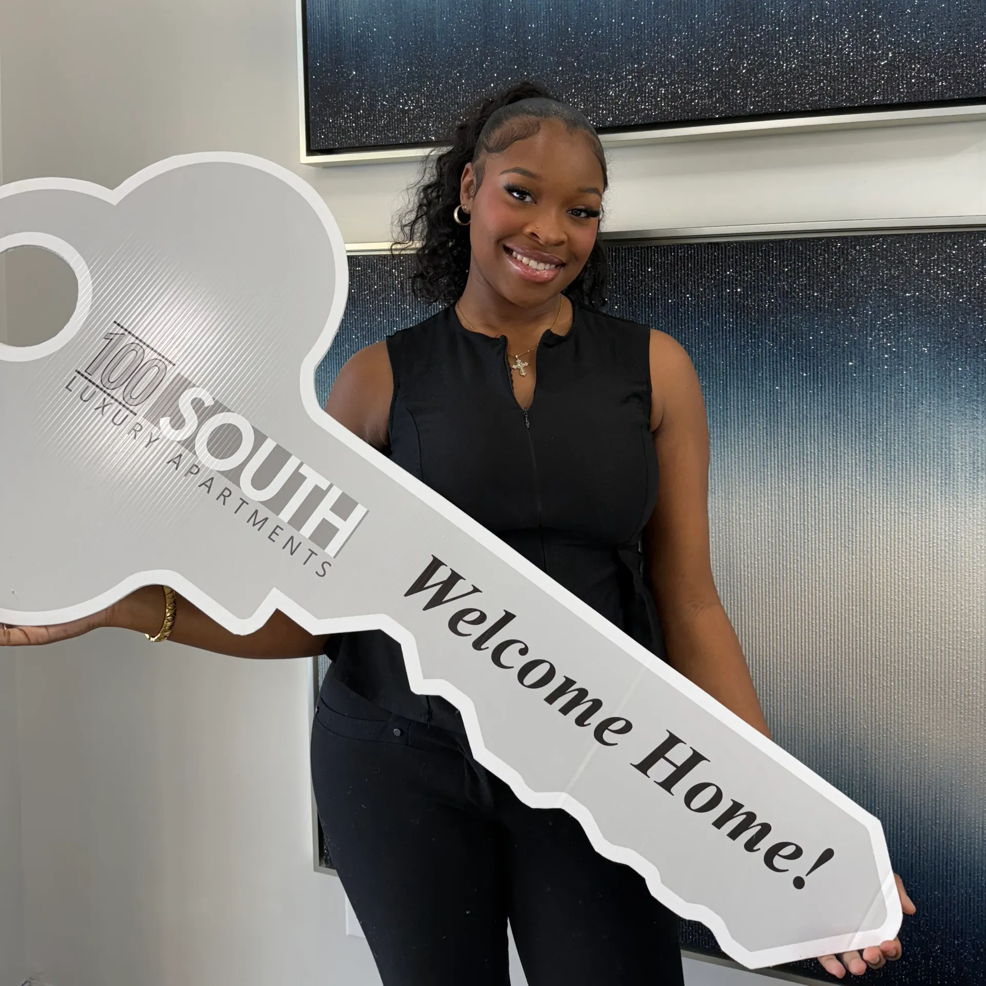 Leasing agent holding welcome key sign at 100 South Apartments in McDonough, GA.