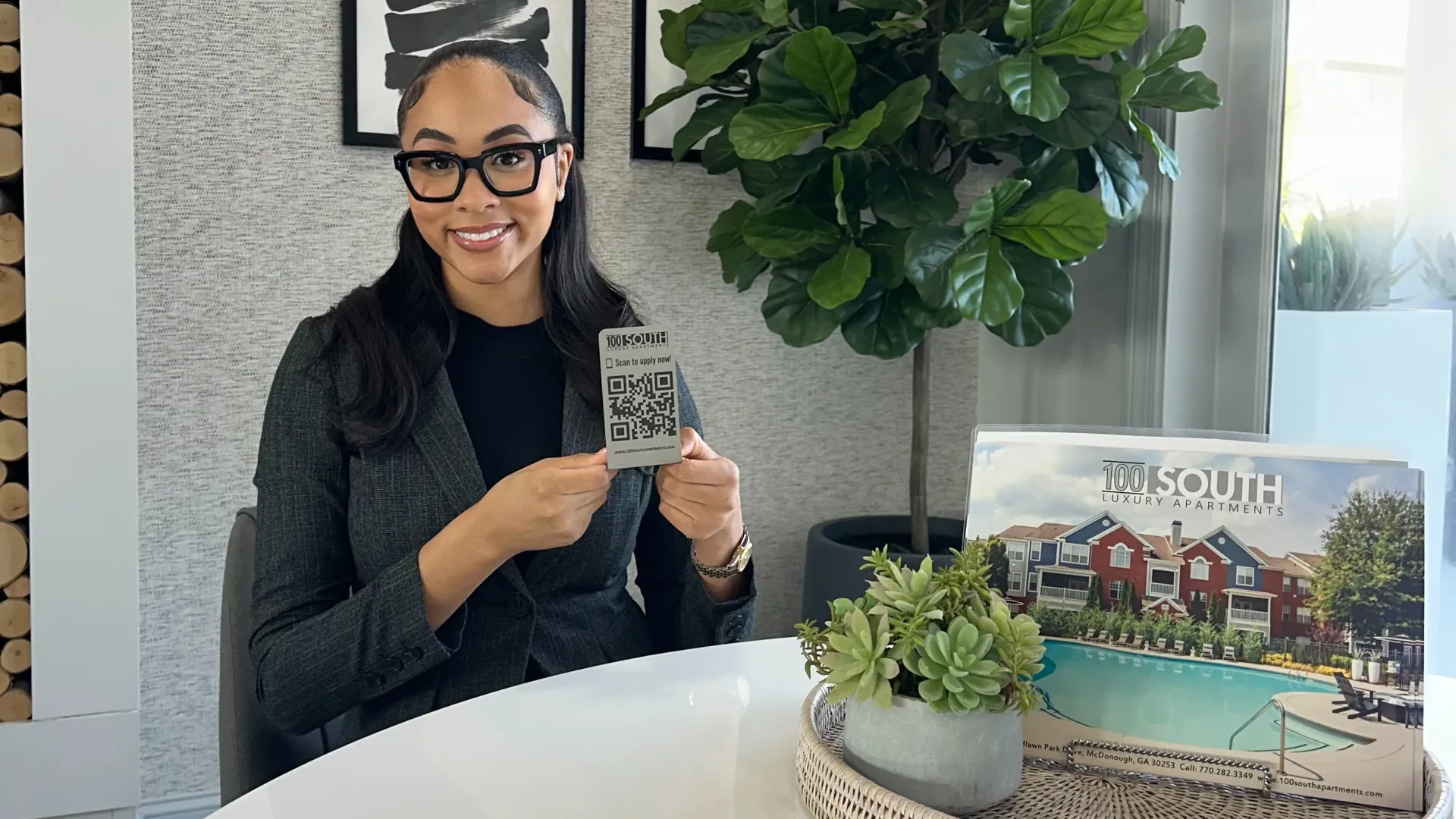 Leasing office team member at 100 South Apartments in McDonough, GA showing QR code to apply online.