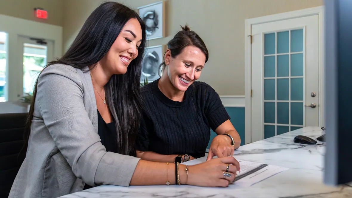 A photo of two people looking over a lease and one of them is signing it.
