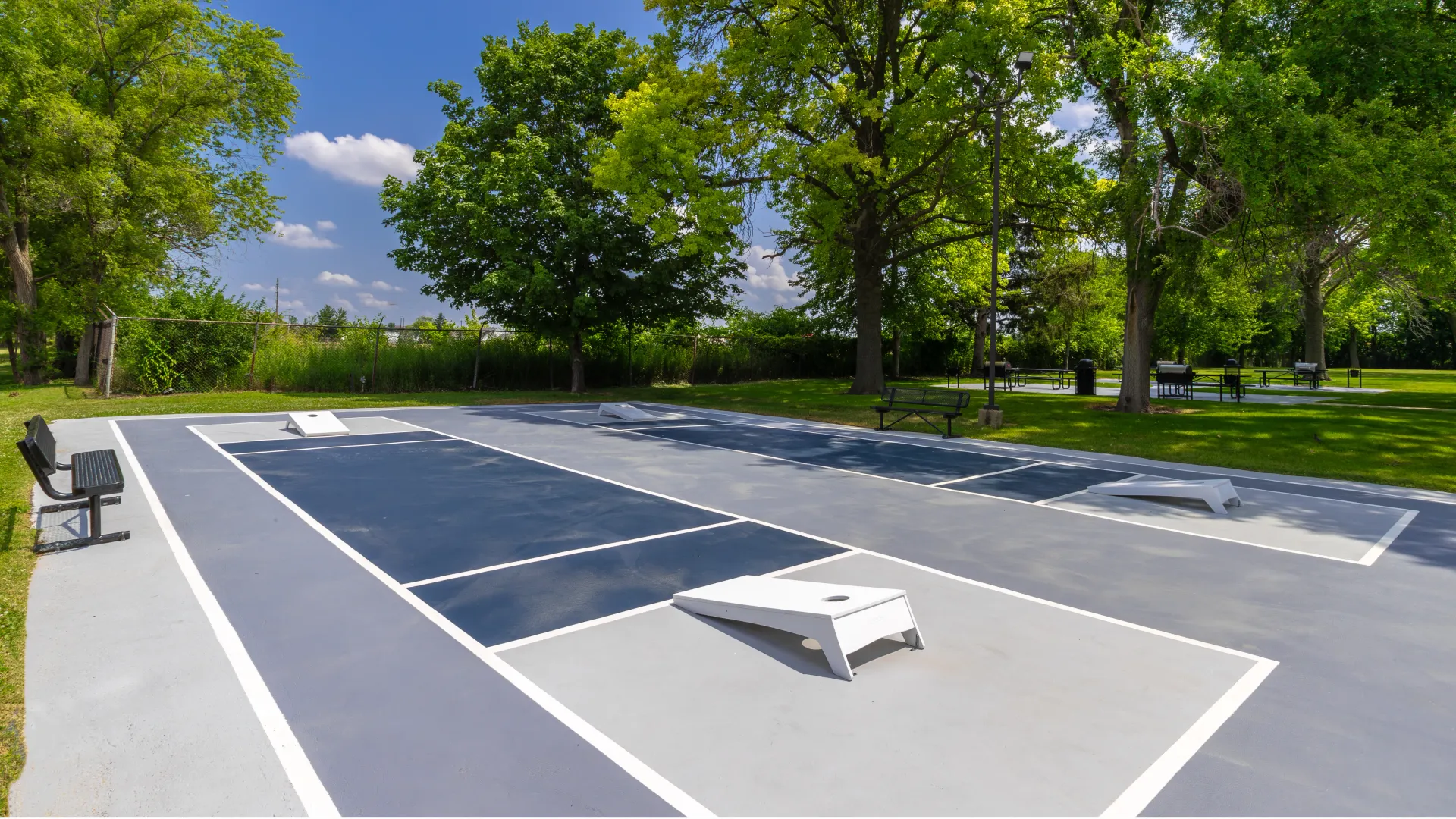 Outdoor cornhole courts at Onyx Apartments, surrounded by lush greenery and equipped with seating areas, offering a space for socializing and outdoor fun.