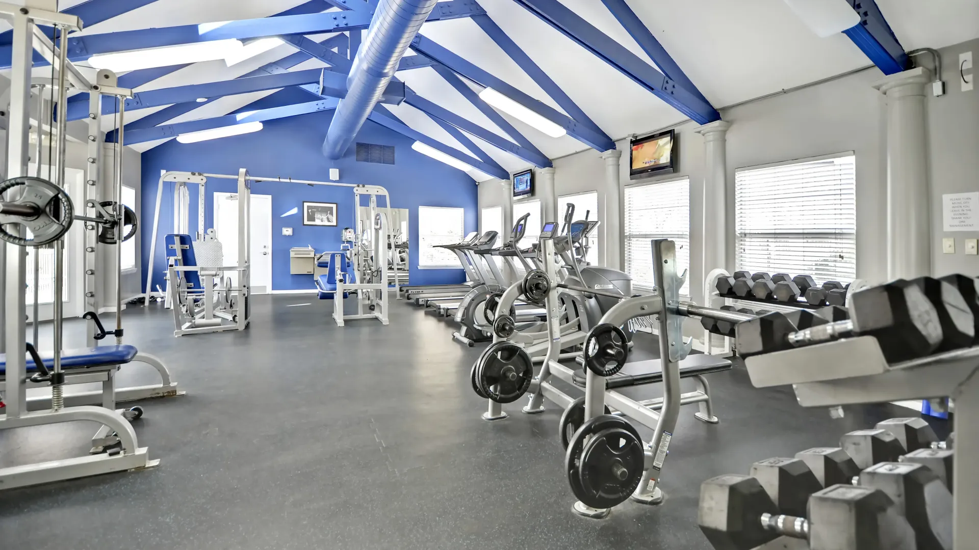 A well-lit gym with equipment and vaulted ceiling. 