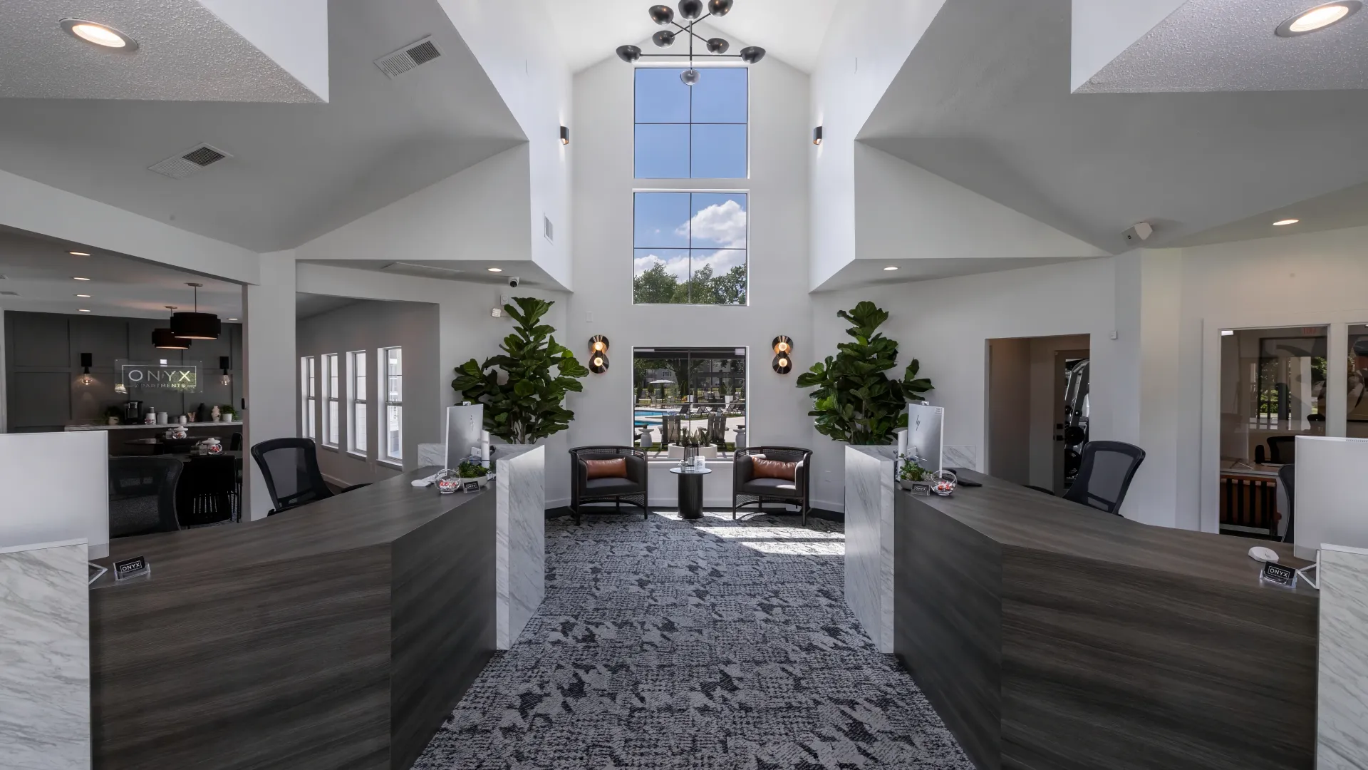 Interior view of the Onyx Apartments leasing office featuring modern design, high ceilings, large windows, stylish furnishings, and a welcoming reception area.