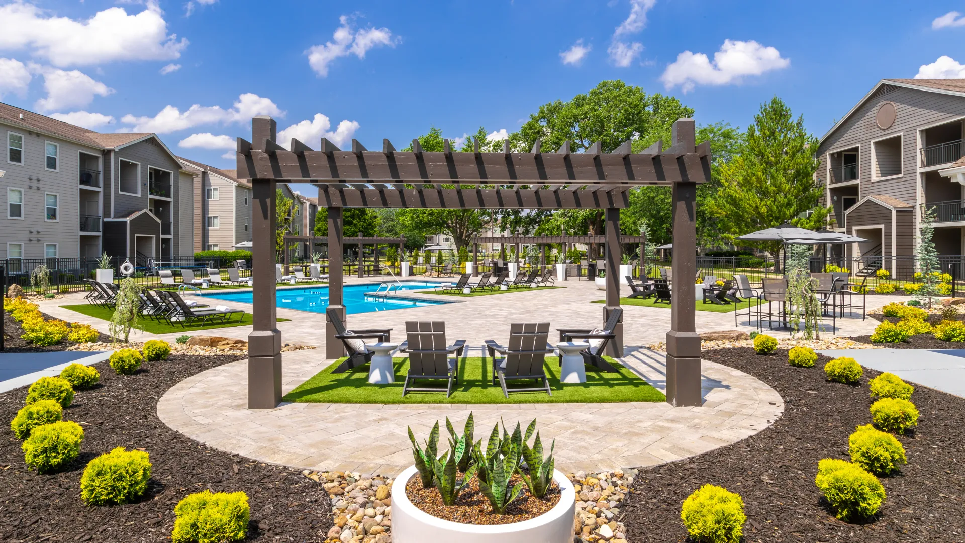 Serene poolside retreatfeaturing modern pergolas, cozy seating areas, lush landscaping, and beautiful apartment buildings, offering a perfect setting for relaxation and enjoyment.