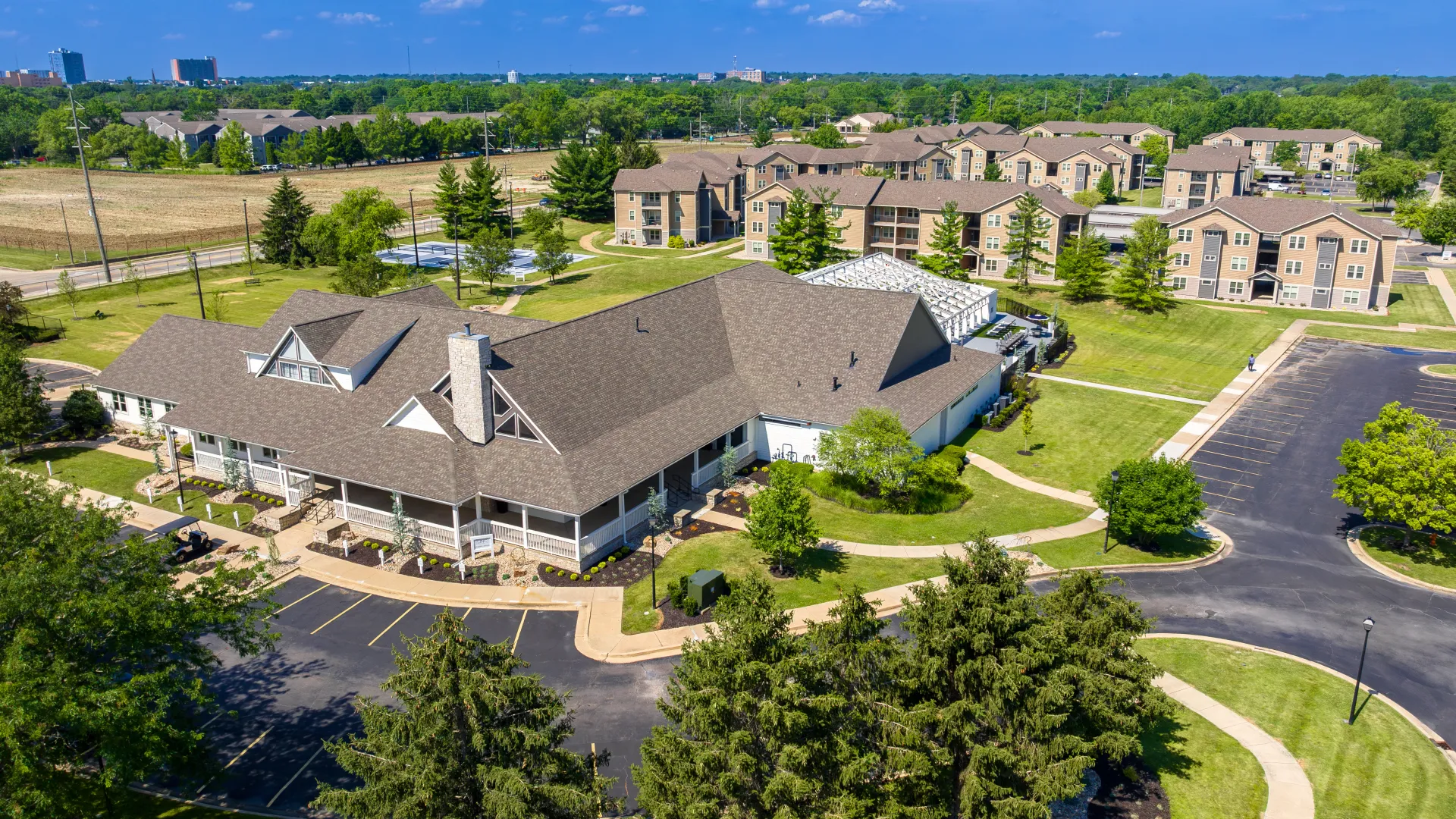 Aerial view of The LINC Apartments community in Urbana, IL, showcasing the expansive green spaces, modern apartment buildings, and central clubhouse with surrounding amenities.