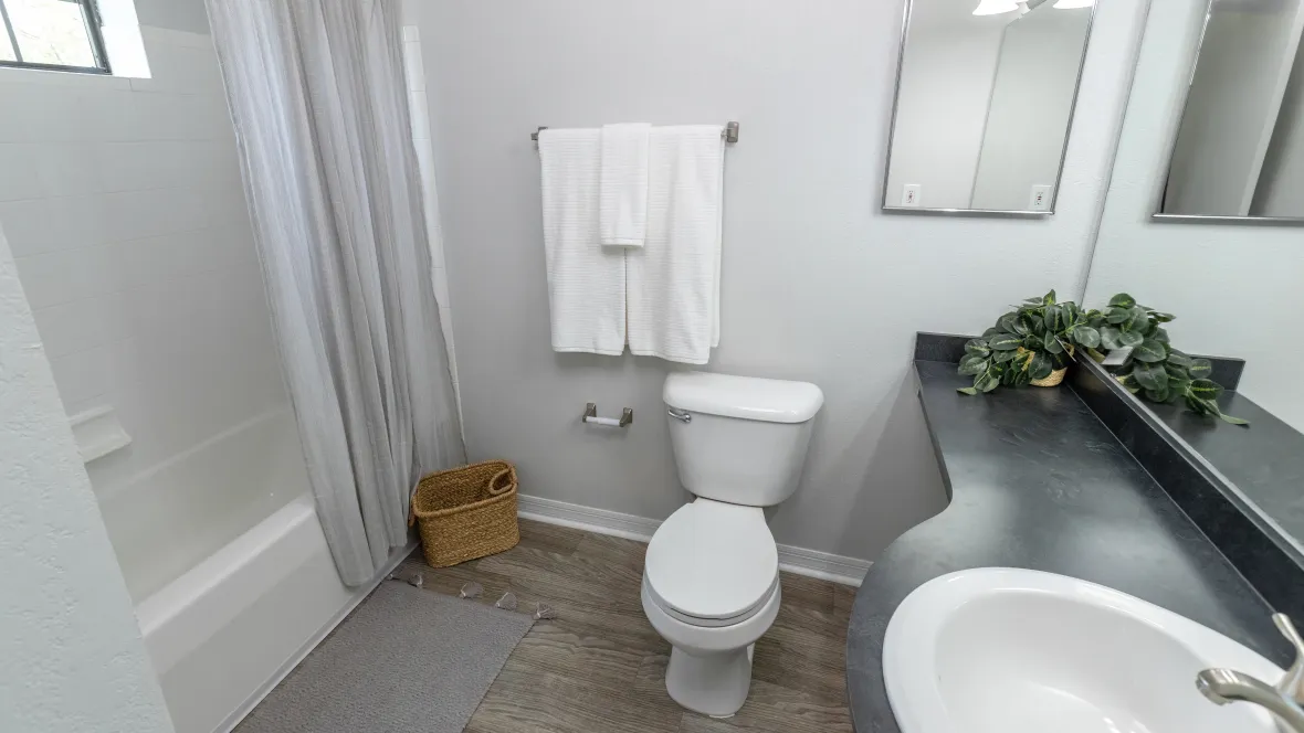 Inviting spacious private bathroom with beautiful flooring and large mirror.