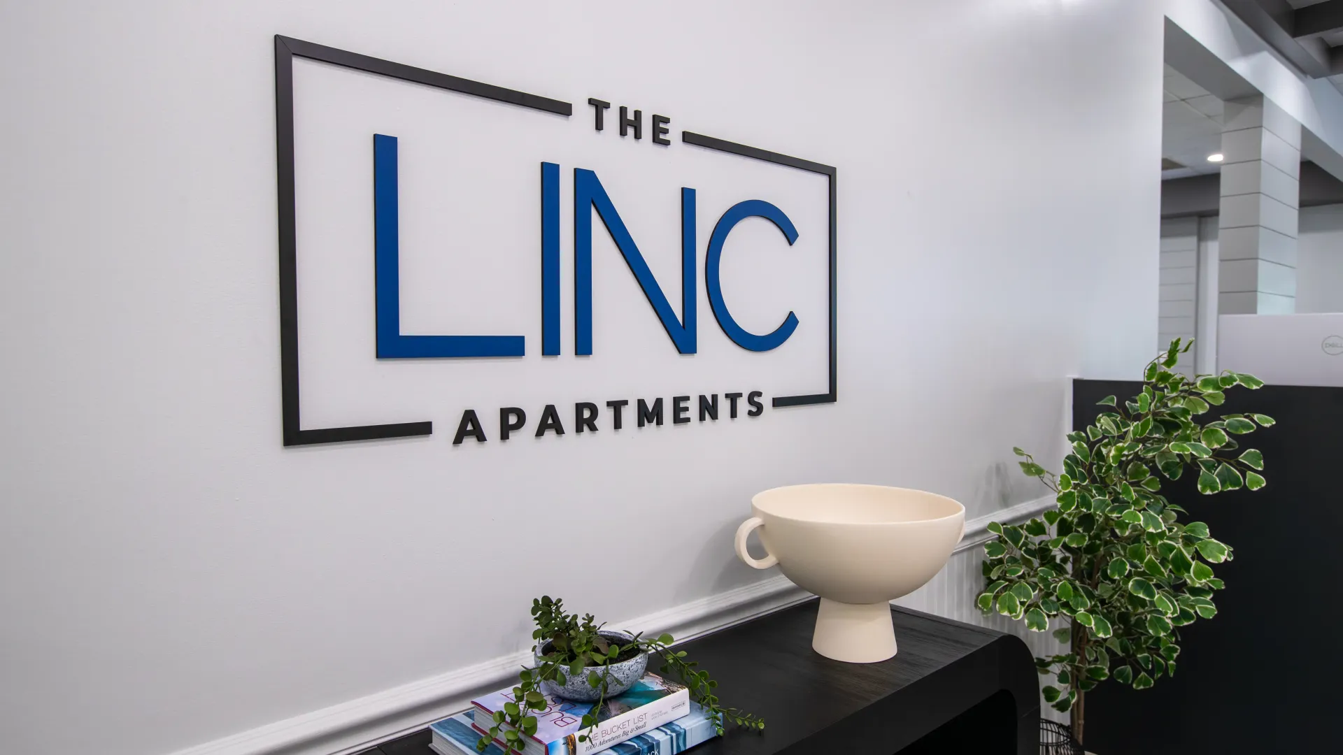 Close-up view of The LINC Apartments sign in the leasing office, featuring modern decor and a welcoming atmosphere.
