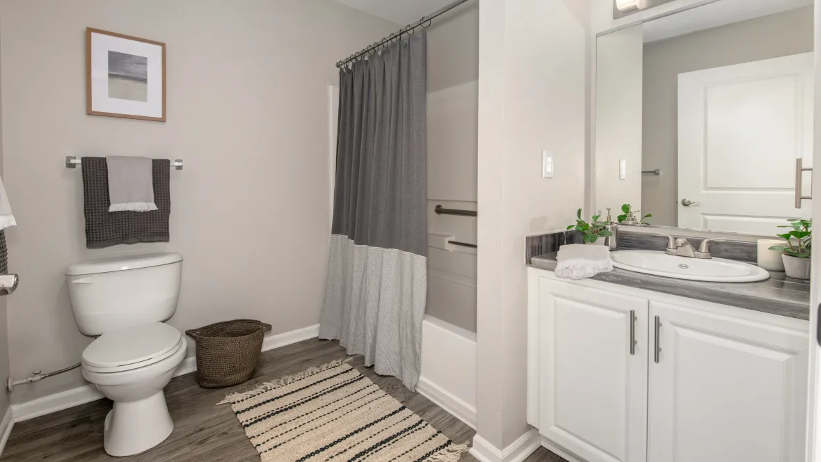 A lavish bathroom with granite-style counters, modern vanity lighting, and a spacious shower/tub