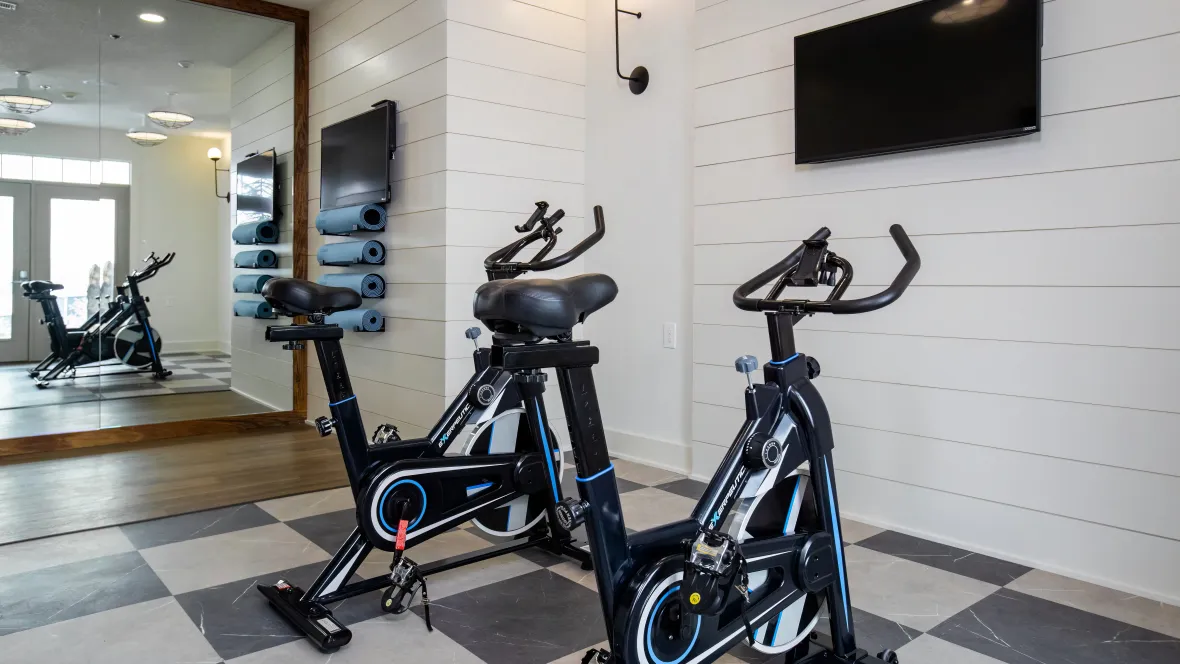 Two spinning bikes facing a smart TV for a customizable workout experience.