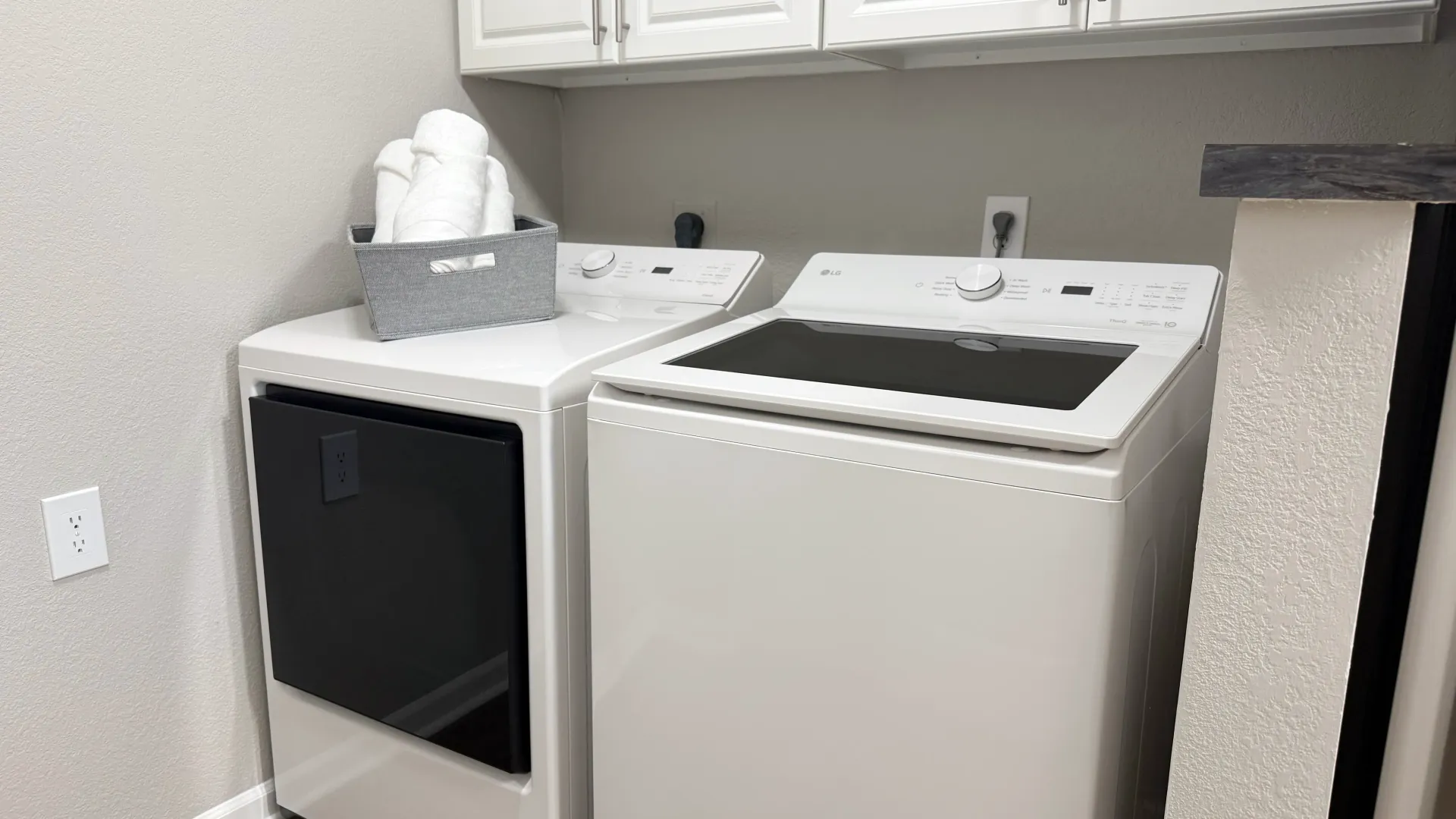 In-home laundry area at Lenox West featuring a full-size washer and dryer with overhead storage cabinets.