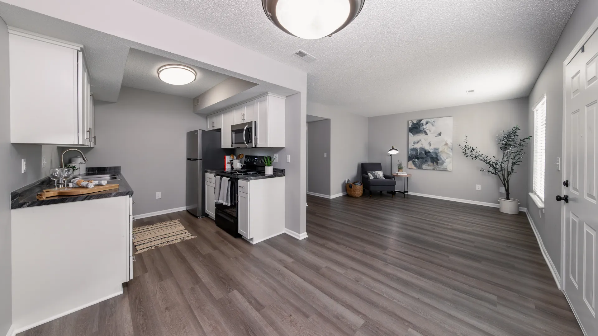 An open-concept living area featuring a modern kitchen with stainless steel appliances and a spacious living room with hardwood floors and stylish decor.