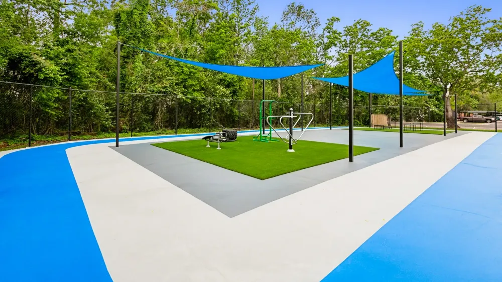 Outdoor fitness equipment on a bright blue court with sun shades
