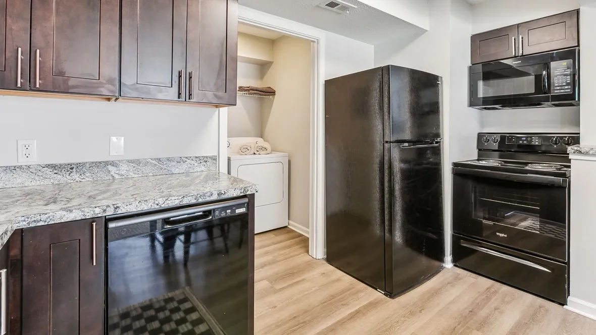 A stylish kitchen equipped with full-size appliances, including a refrigerator, mounted microwave, oven, dishwasher, and the added convenience of a washer and dryer adjacent to the kitchen.
