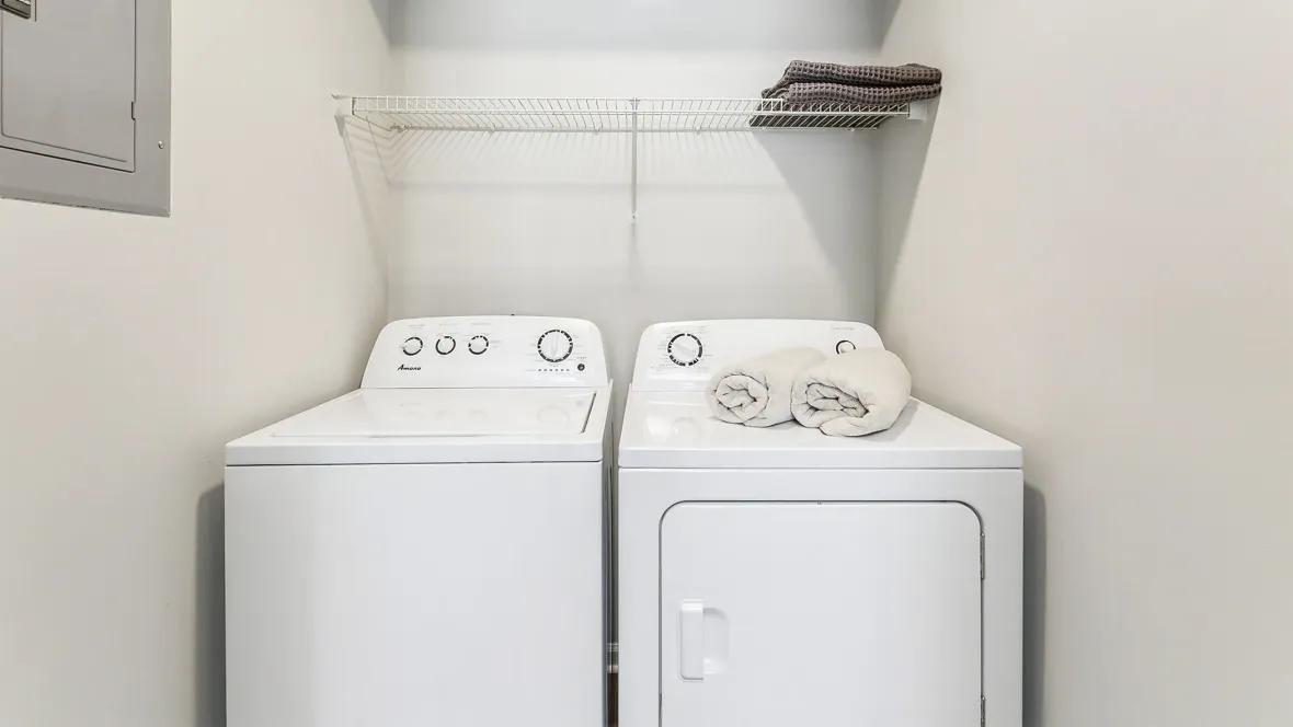 Laundry appliances in a dedicated laundry room, setup with customized open wire shelving above the washer and dryer.