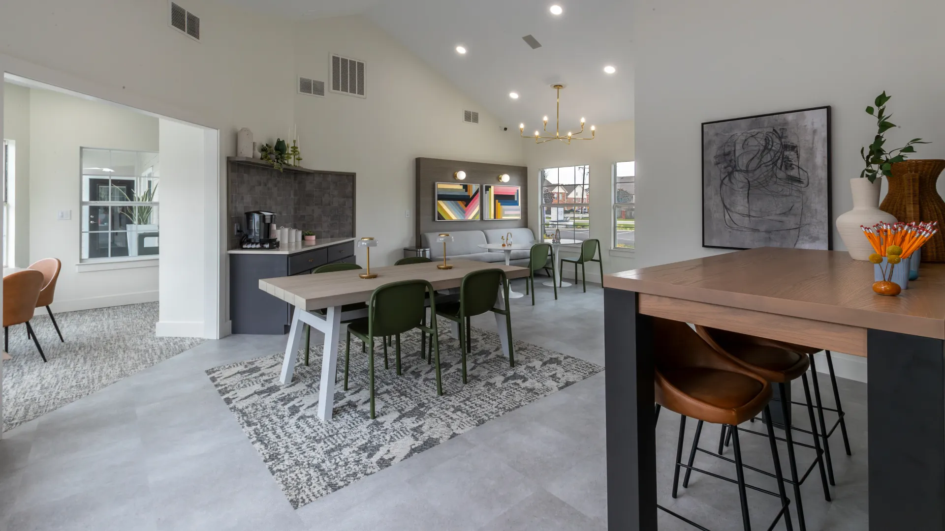 A modern study lounge featuring large tables with individual study lamps, comfortable seating, a coffee station, and contemporary artwork. The room is well-lit and designed for a productive study environment.